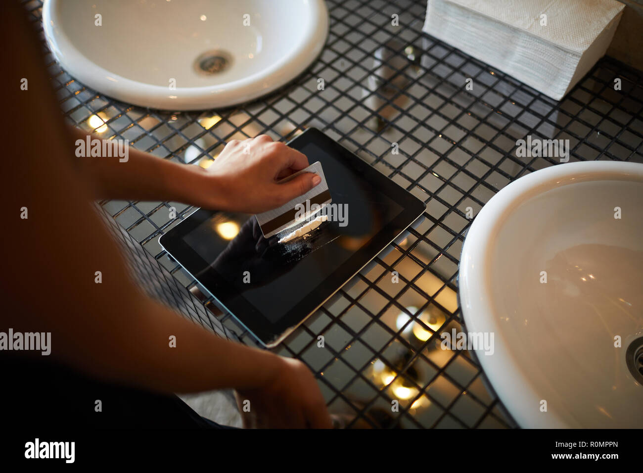 Giovane donna linea di produzione di cocaina prima di sbuffare è off display touchpad nella stanza da bagno Foto Stock