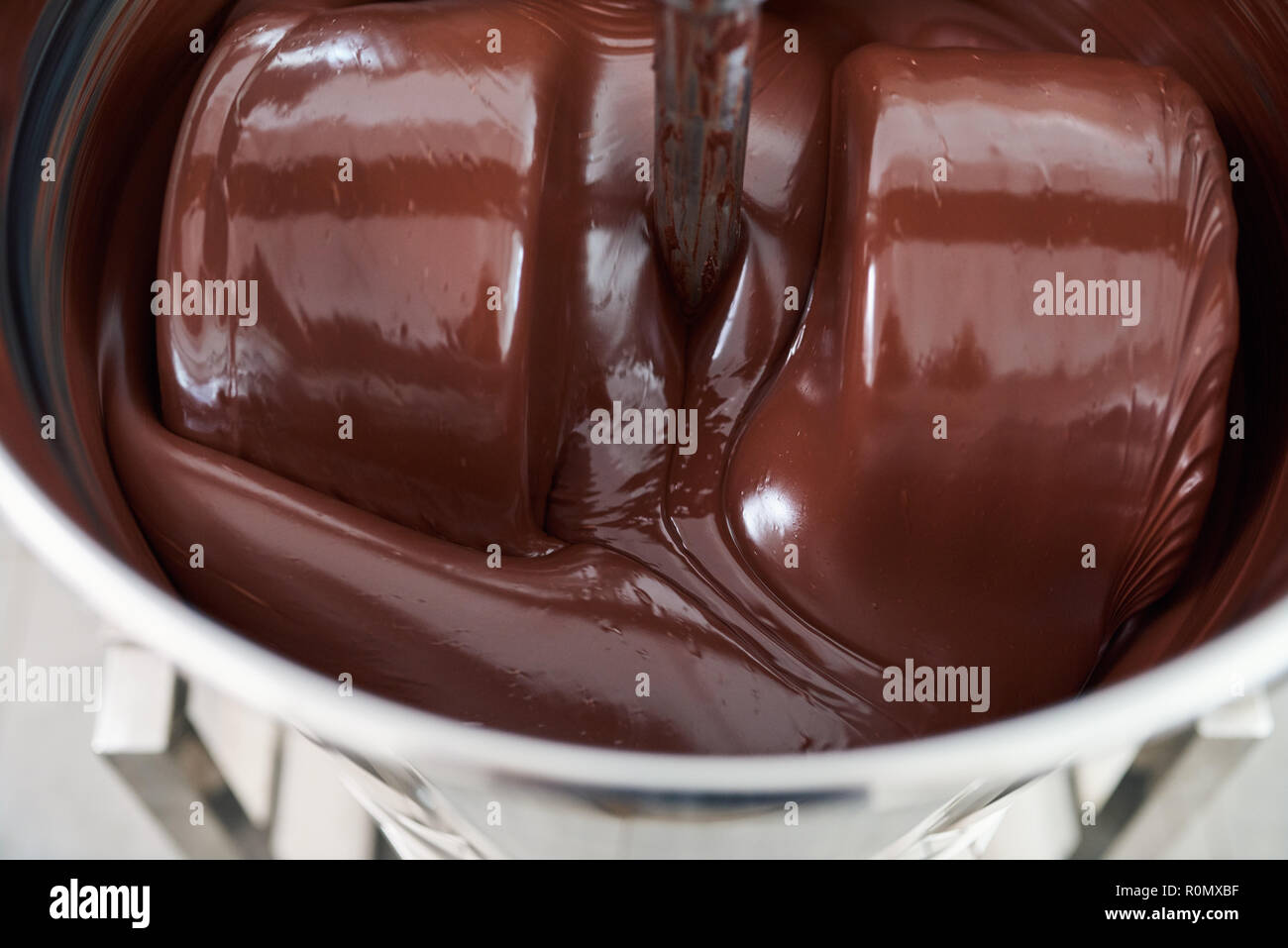 Il cioccolato fuso mescolando in un acciaio inossidabile miscelatore Foto Stock