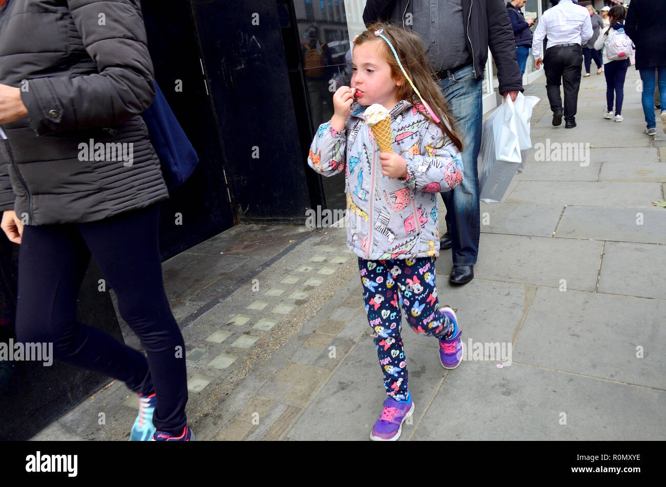 Bambina di mangiare un cono gelato in Street, Londra, Inghilterra, Regno Unito. Foto Stock