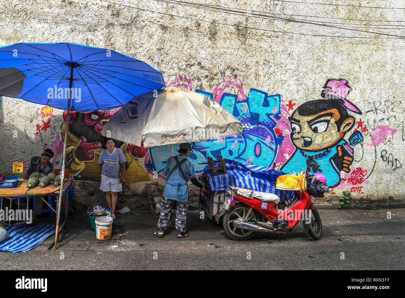 Thai commercianti di strada e la parete grafitti Foto Stock