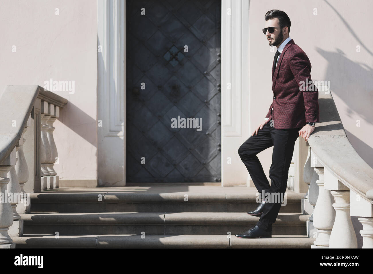 Elegante di moda uomo in nero occhiali da sole in posa all'aperto sulle scale (copia spazio). Foto Stock