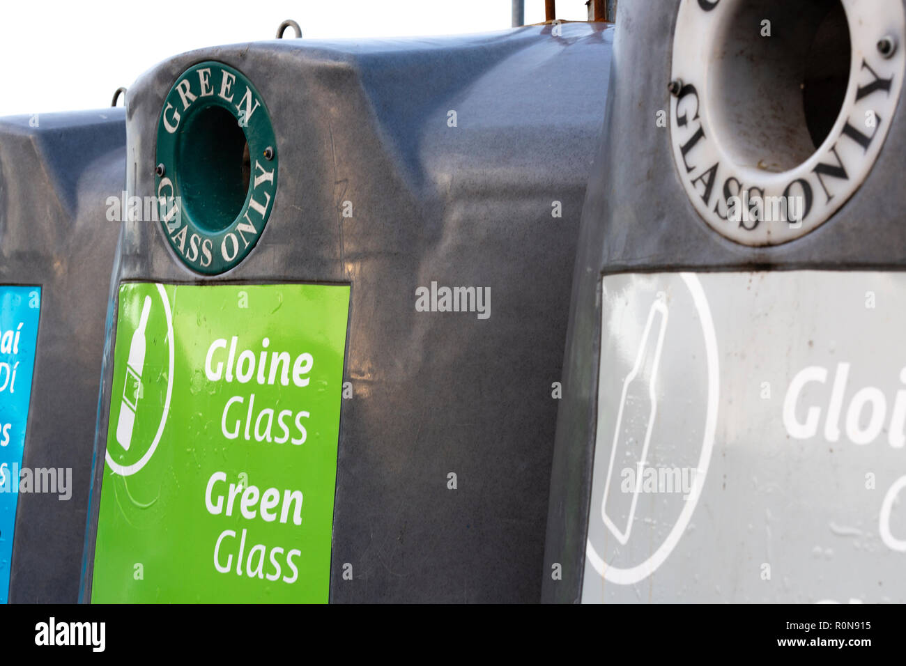Il riciclaggio del vetro raccoglitori di vari colori con scrittura irlandese Foto Stock