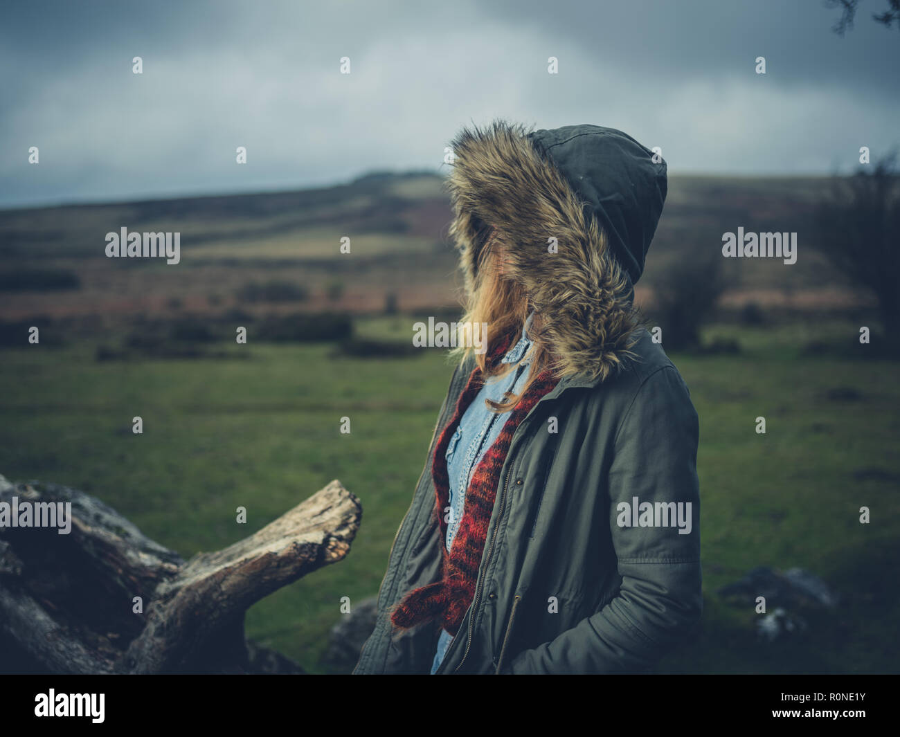 Una giovane donna che indossa un cappotto pesante è in piedi sul moor Foto Stock