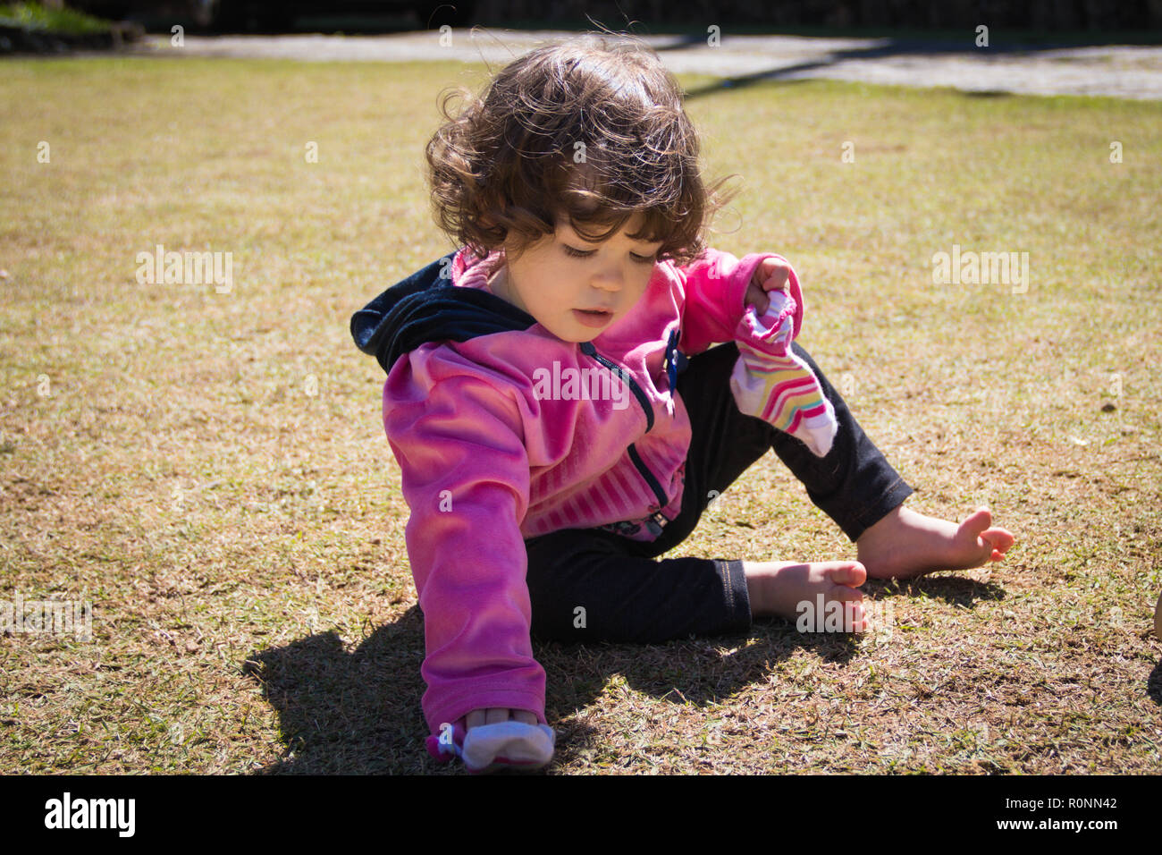 Ragazza seduta in un parco tenendo le sue calze Foto Stock