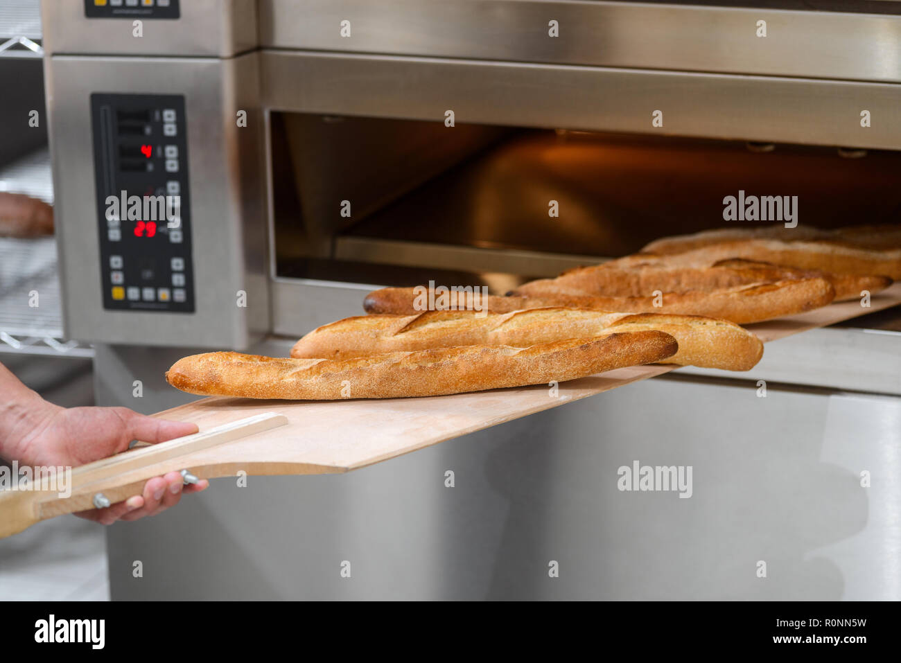 Prendendo il pane al di fuori del forno Foto Stock