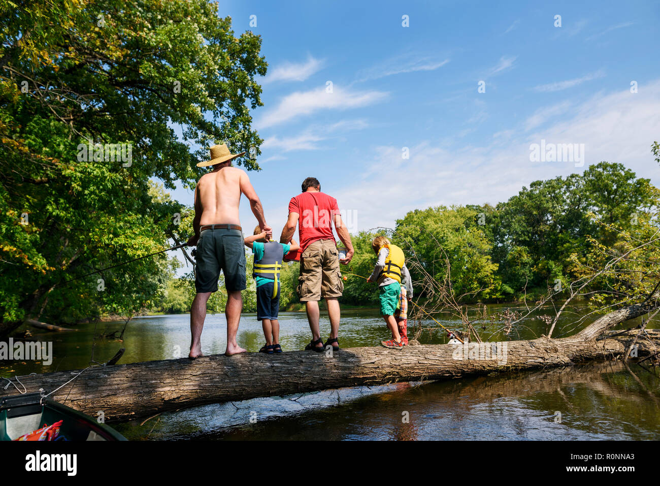 Due uomini e tre bambini in piedi su un albero caduto pesca, Stati Uniti Foto Stock