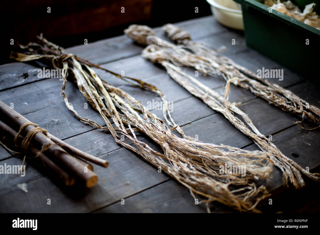 Grappoli piccoli e di filiali e di fibre vegetali su un tavolo, la questione organica utilizzata nella fabbricazione di carta Washi. Foto Stock