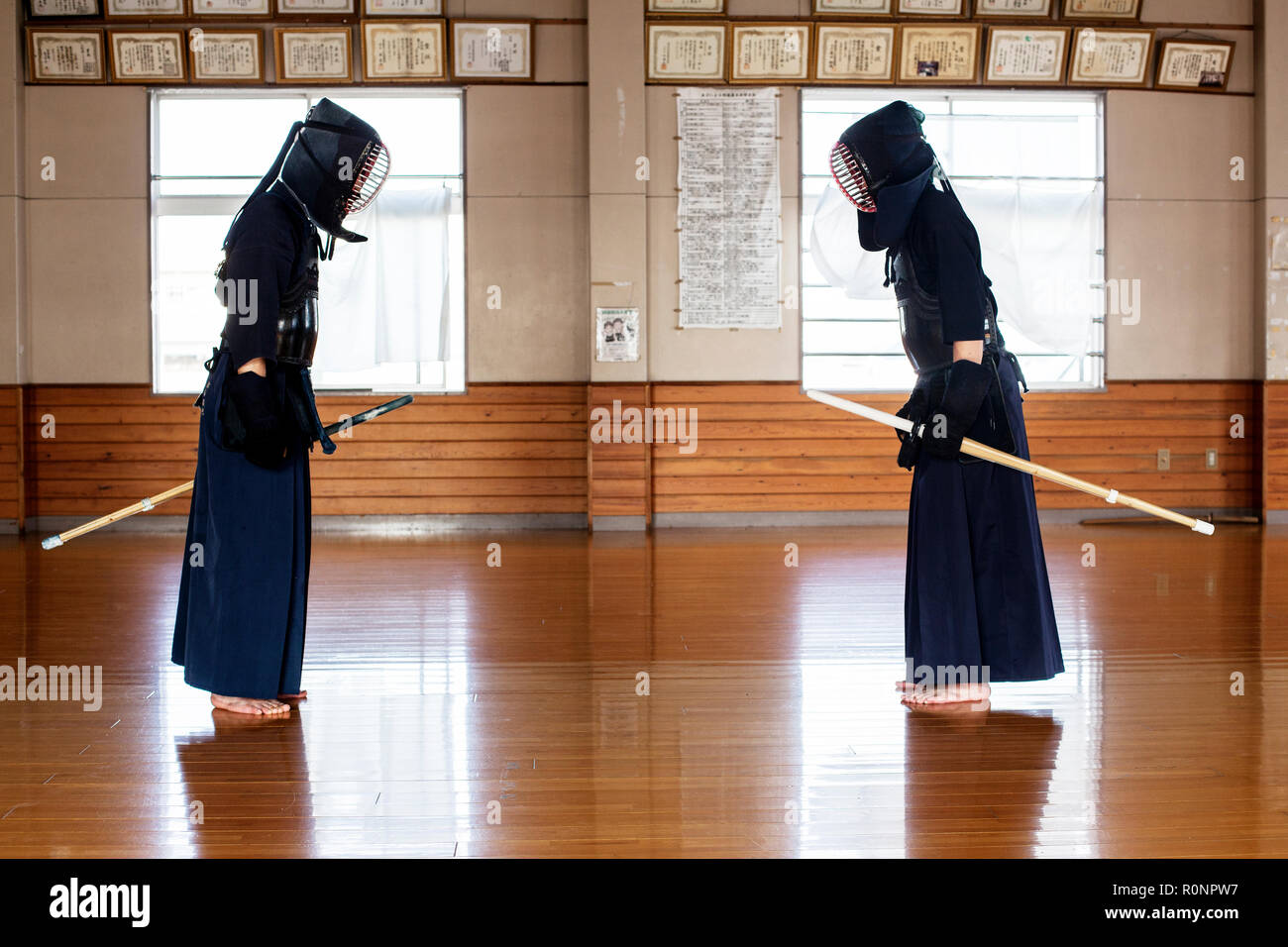 Giapponese Kendo fighters in piedi di fronte a ogni altro sul pavimento in legno, piegando e il messaggio di saluto. Foto Stock