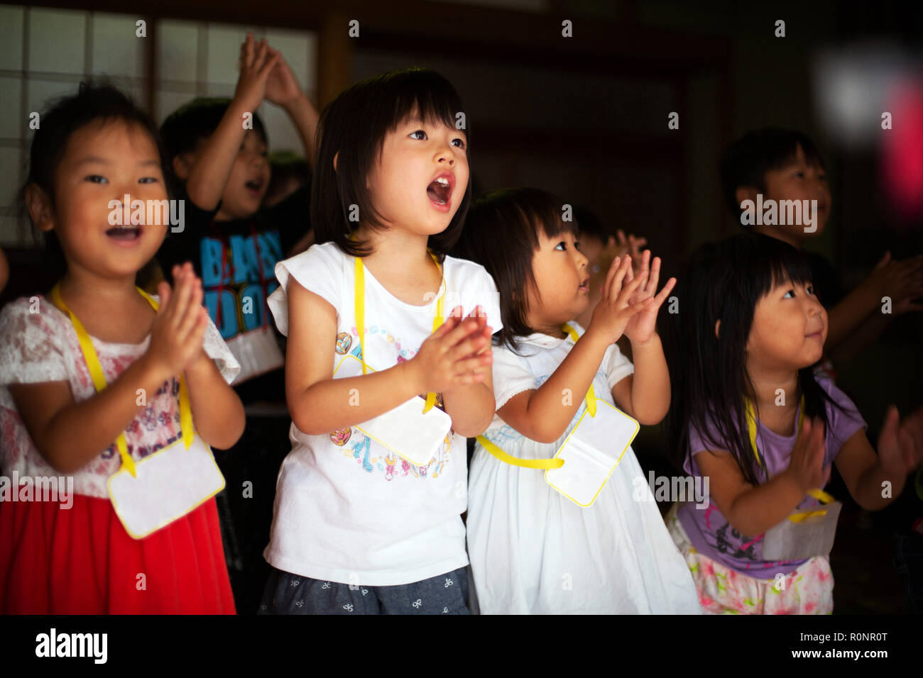 Gruppo di bambini, ragazzi e ragazze cantando e battendo le mani insieme in un tempio. Foto Stock