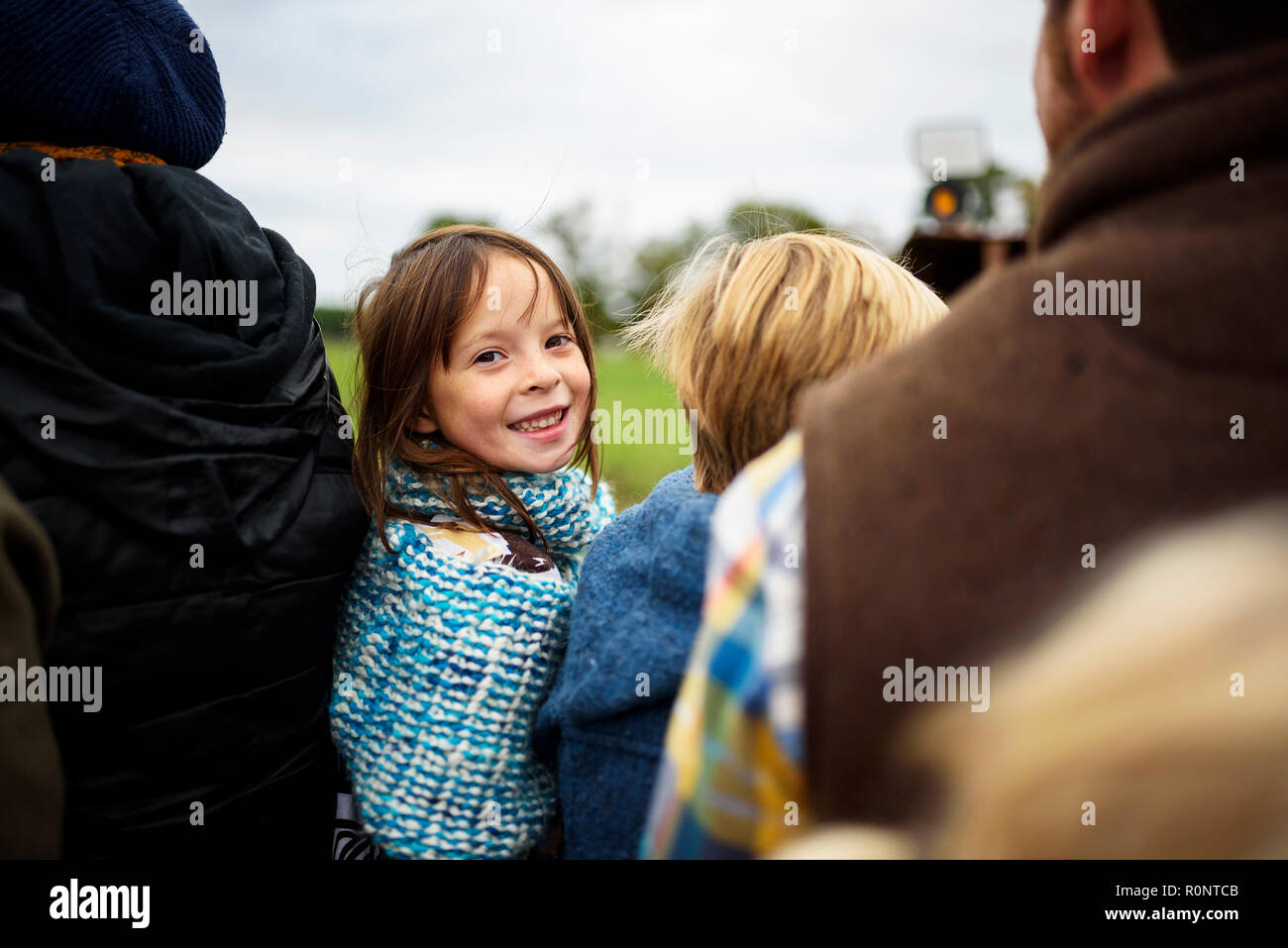 Sorridente ragazza seduta in un carro con la sua famiglia guardando sopra la sua spalla Foto Stock