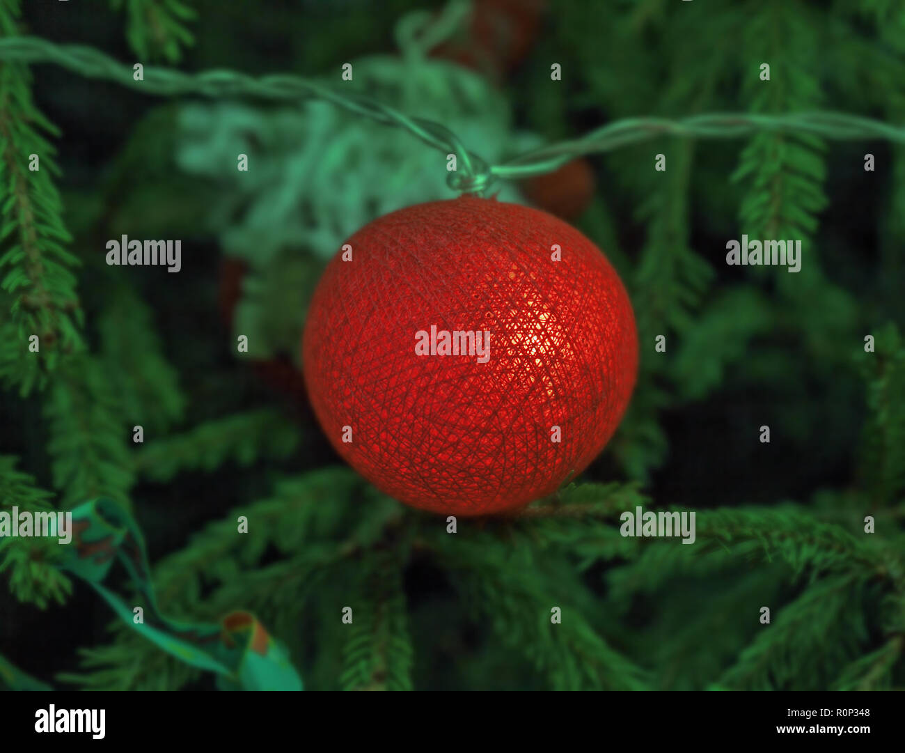 Arancione incandescente palla di filettature su albero di Natale in verde scuro Foto Stock