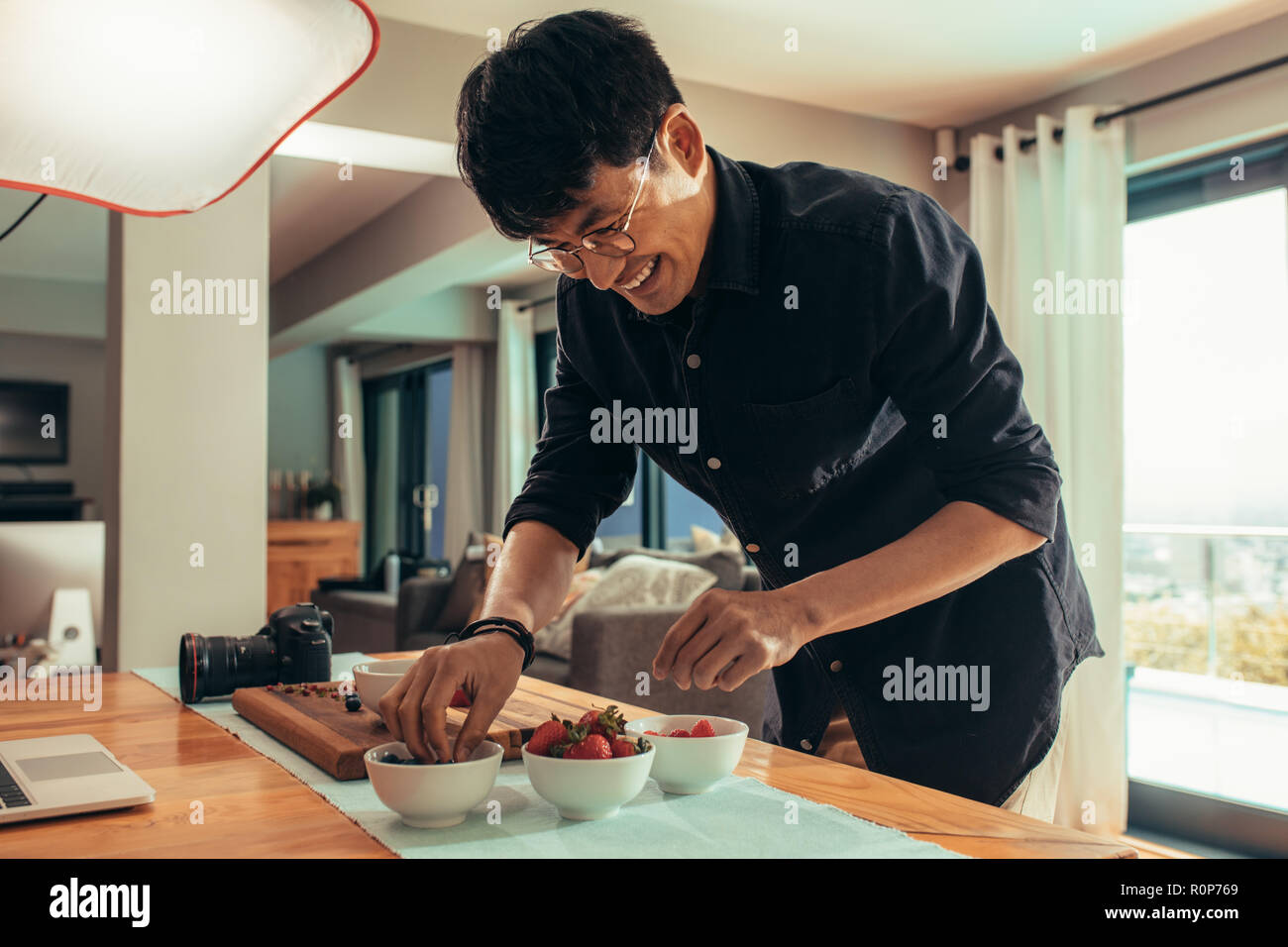 Sorridente fotografo alimentare cibo stile sulla tavola per sparare. Fotografo asiatico prepara il cibo per inserzione photoshoot. Foto Stock