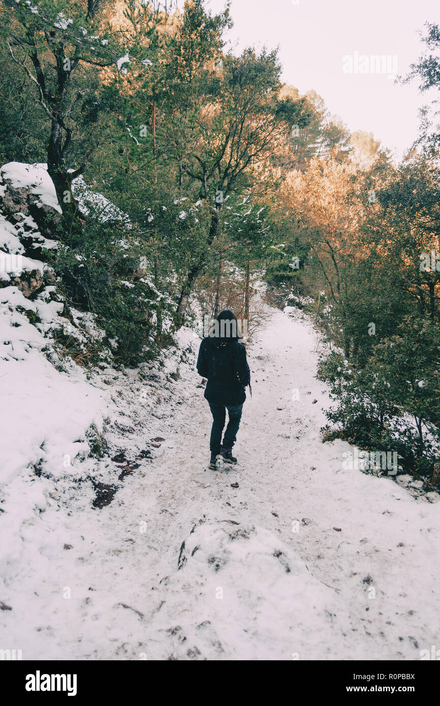 Ragazza camminare sulla sua schiena su una montagna innevata trail in inverno Foto Stock