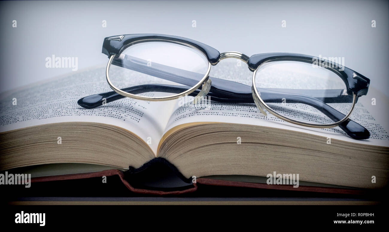 Occhiali vintage su un Libro isolato su sfondo bianco Foto Stock