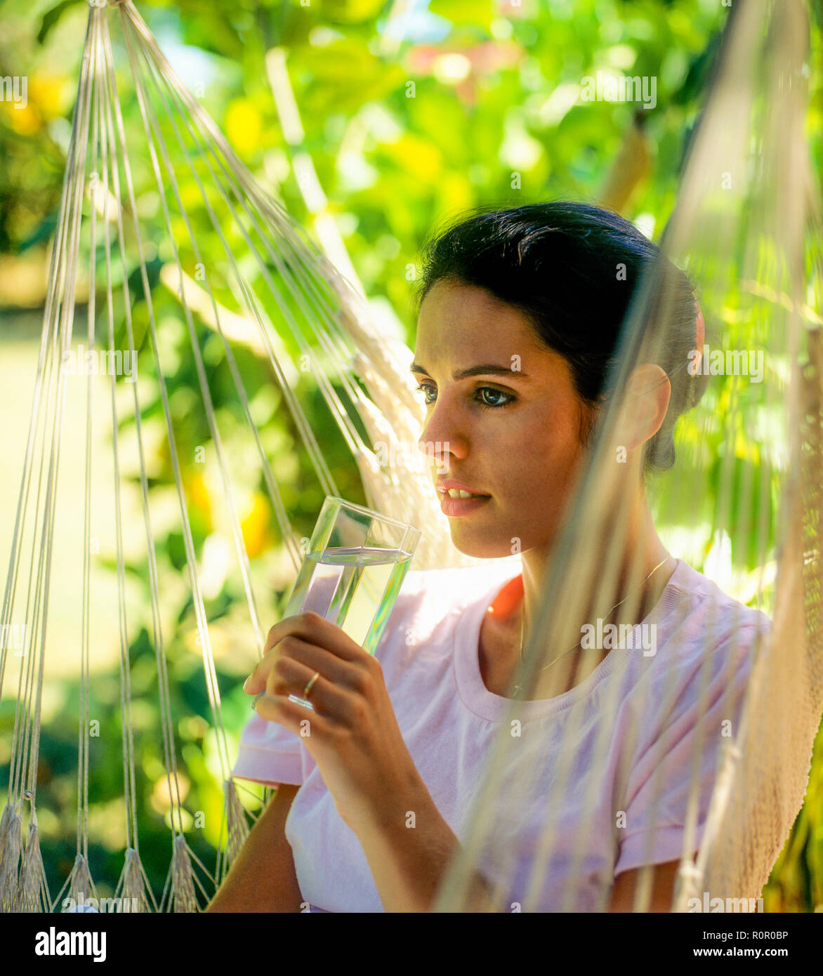 Giovane donna con in mano un bicchiere di acqua, giardino tropicale, Guadalupa, French West Indies, Foto Stock