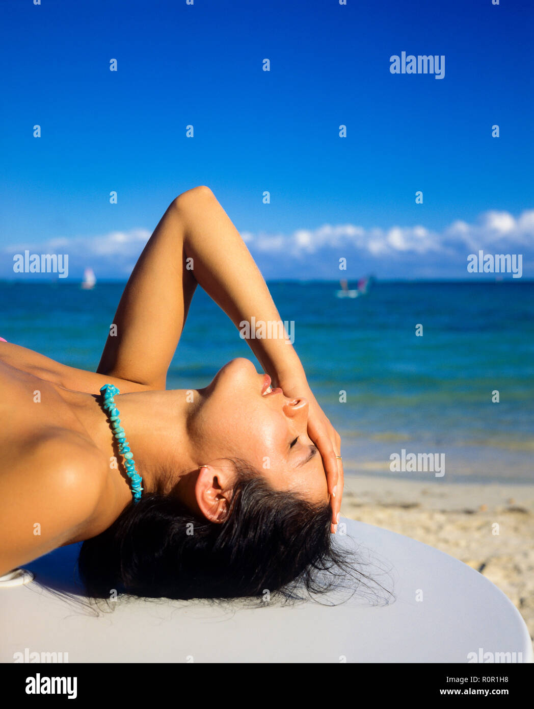 Ritratto di giovane donna a prendere il sole a occhi chiusi, tenendo la testa con la mano, il mare dei Caraibi, Guadalupa, French West Indies, Foto Stock