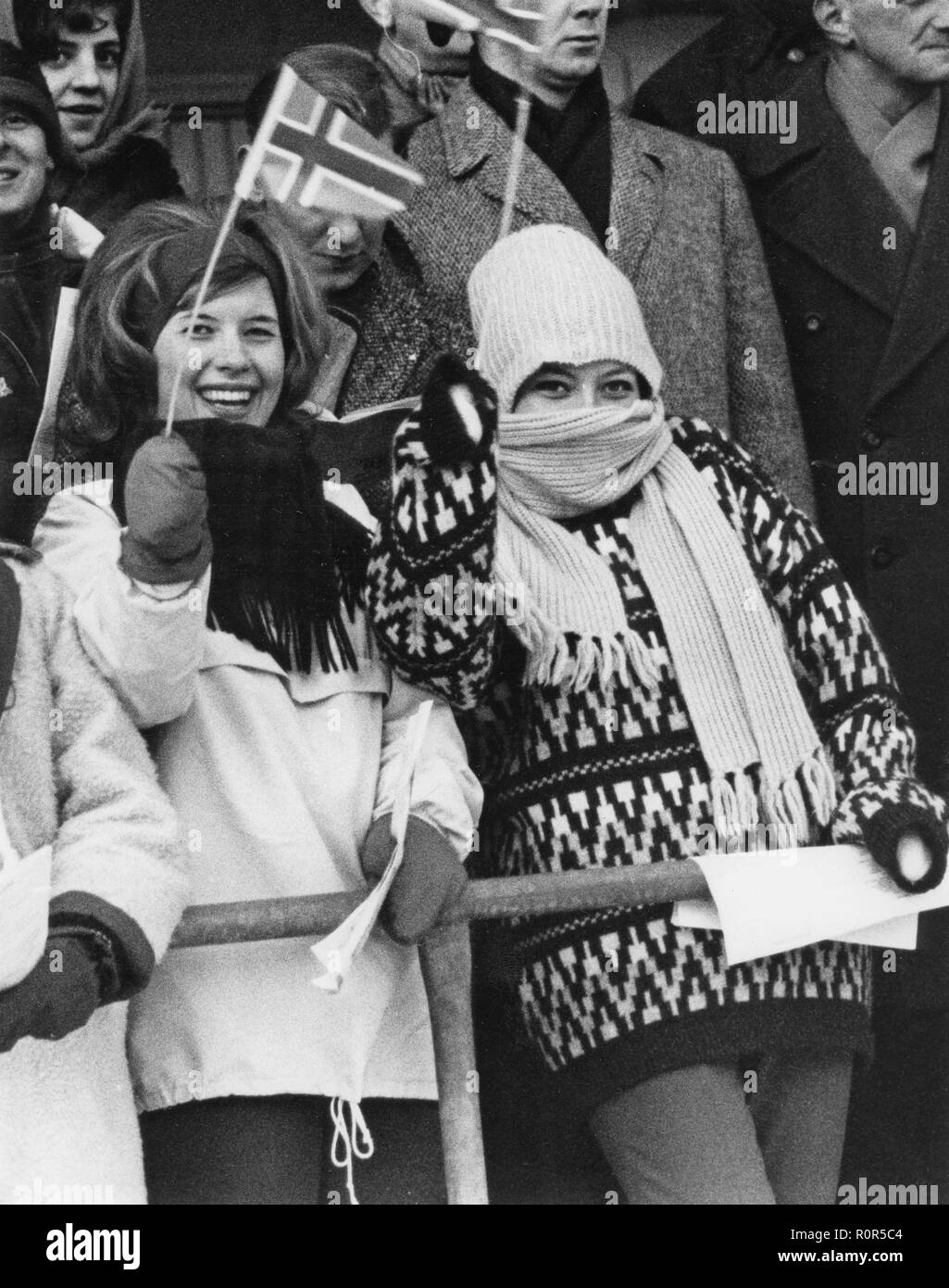 Inverno negli anni sessanta. Due felici le giovani donne sono a fare il tifo per i loro preferiti norvegese con bandiere e acclamazioni. Che indossano vestiti caldi nel freddo. La Svezia 1963 Foto Stock