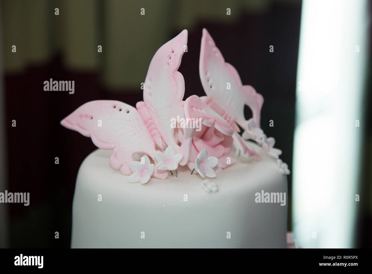 Close up white iced tiered torta di nozze con decorazioni rosa su Foto Stock