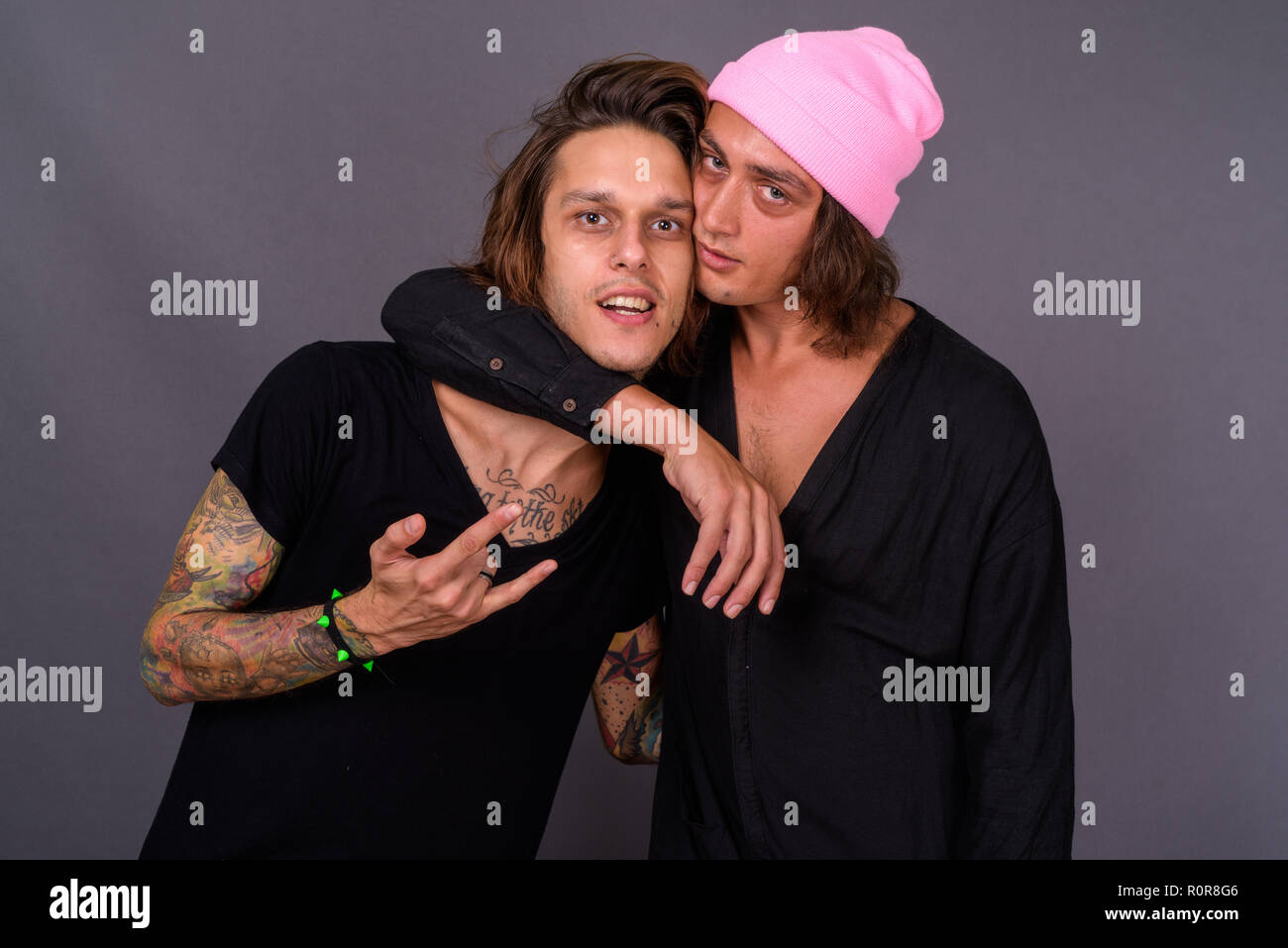Due giovani uomini belli insieme contro lo sfondo grigio Foto Stock