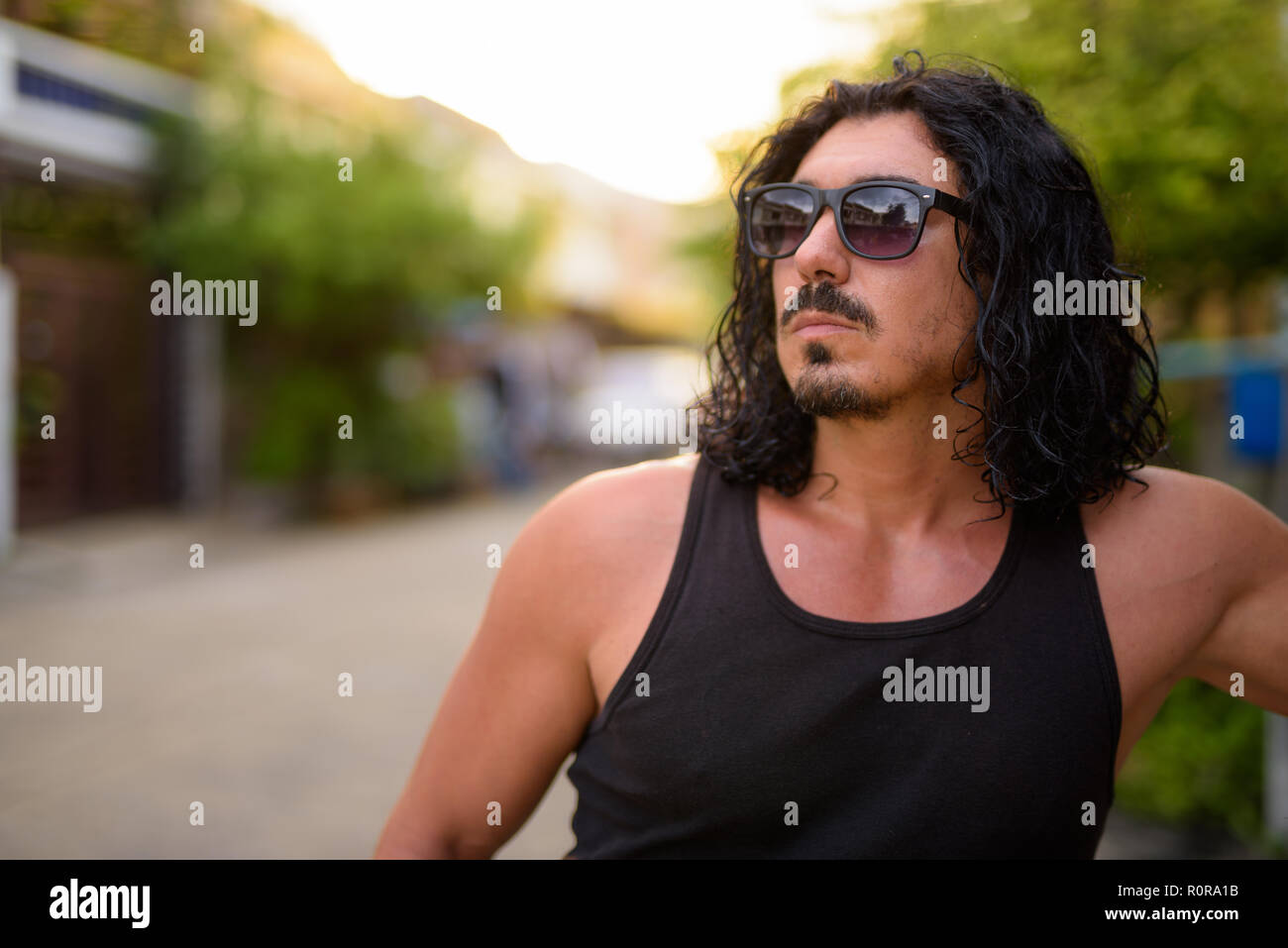 Uomo bello con i capelli ricci e i baffi nelle strade per esterno Foto Stock