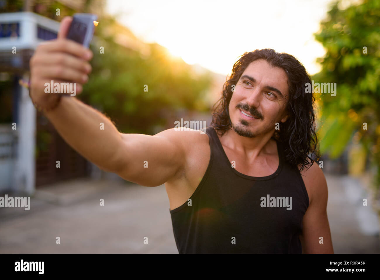 Uomo bello con i capelli ricci e i baffi nelle strade per esterno Foto Stock