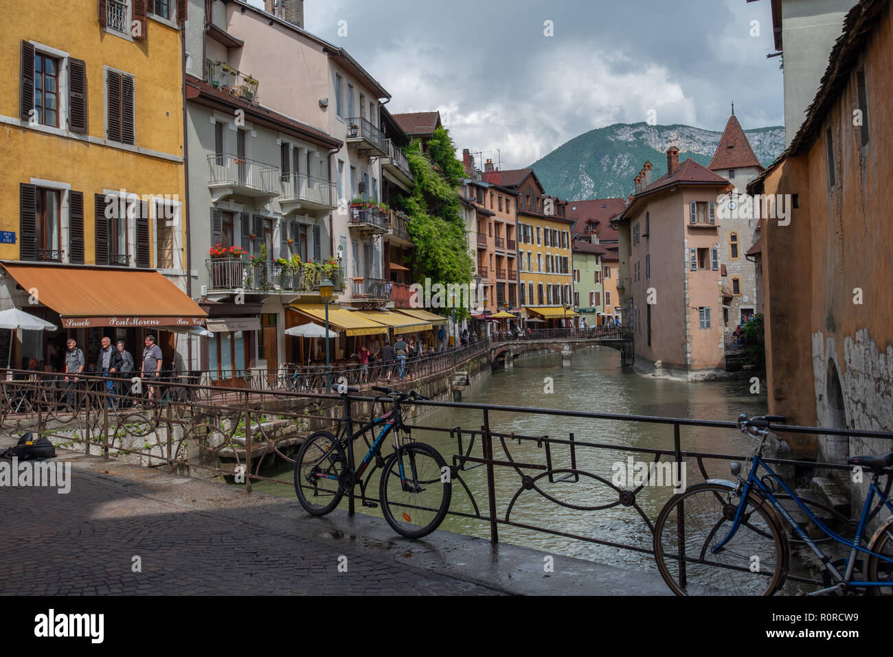 Biciclette incatenato alla ringhiera su un ponte mentre il Thiou fiume scorre attraverso la pittoresca Annecy, Francia. Foto Stock
