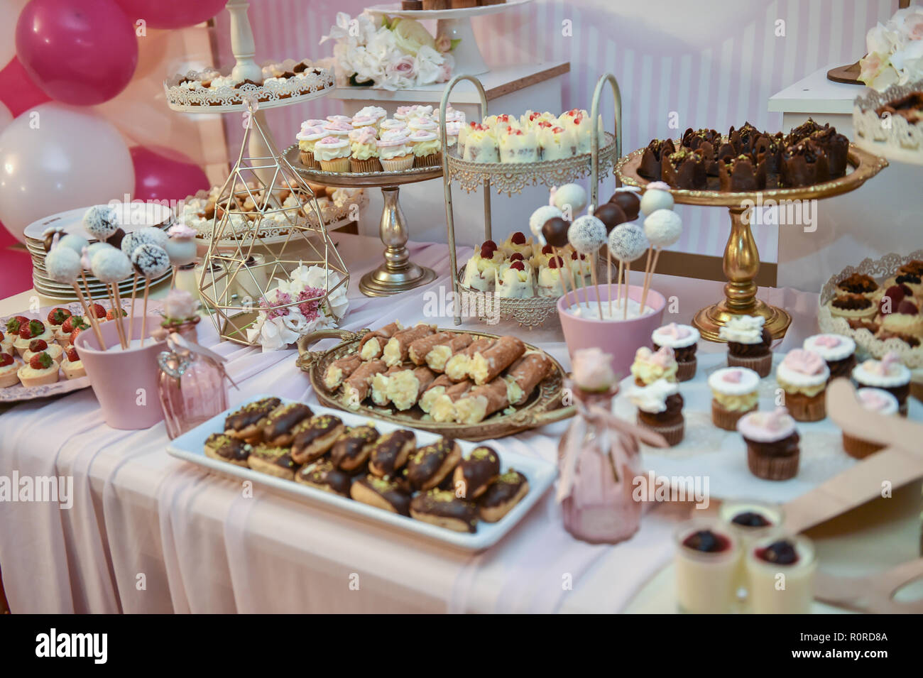 Decorazioni per matrimoni con colori pastello e tortini, meringhe, muffin e macaron. Elegante e lussuoso evento disposizione con amaretti colorati. Foto Stock