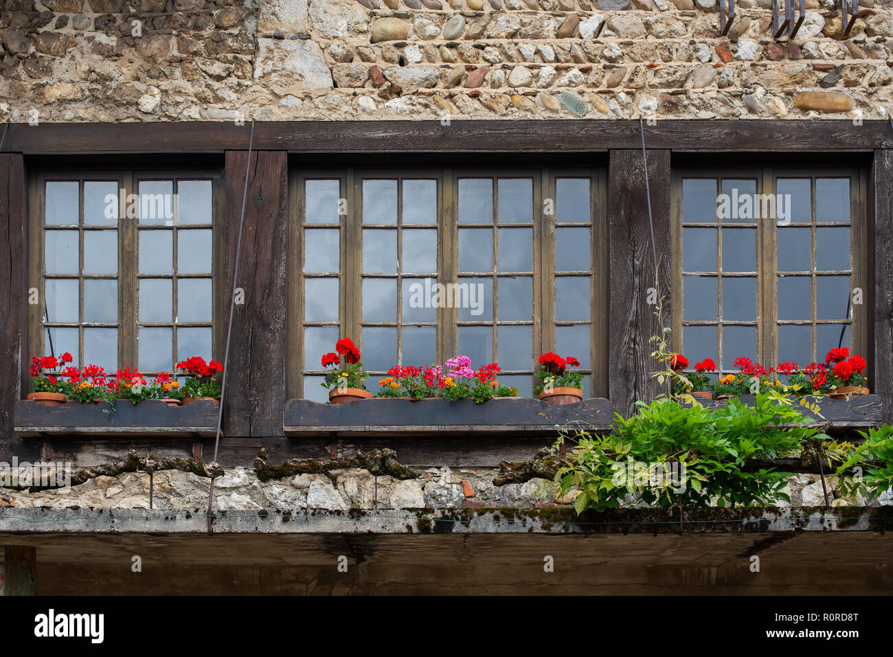 Finestra con gerani rossi finestre lungo una strada nella bellissima zona collinare medievale città murata di PEROUGES, Francia Foto Stock
