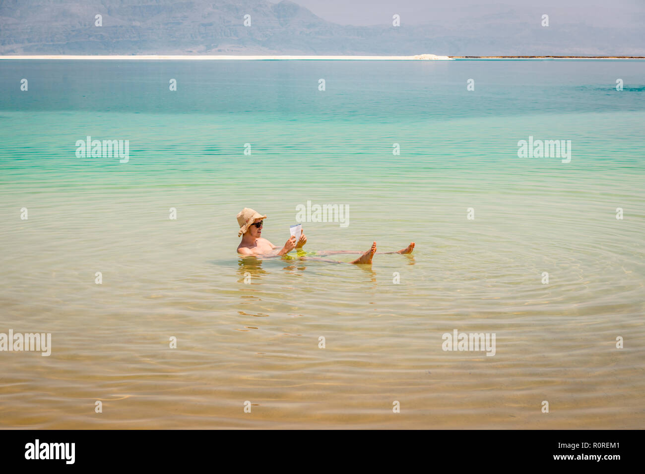 L'uomo la balneazione nel Mar Morto e la lettura, Ein Bokek Beach, il Mar Morto, la Kalia Beach, Israele Foto Stock