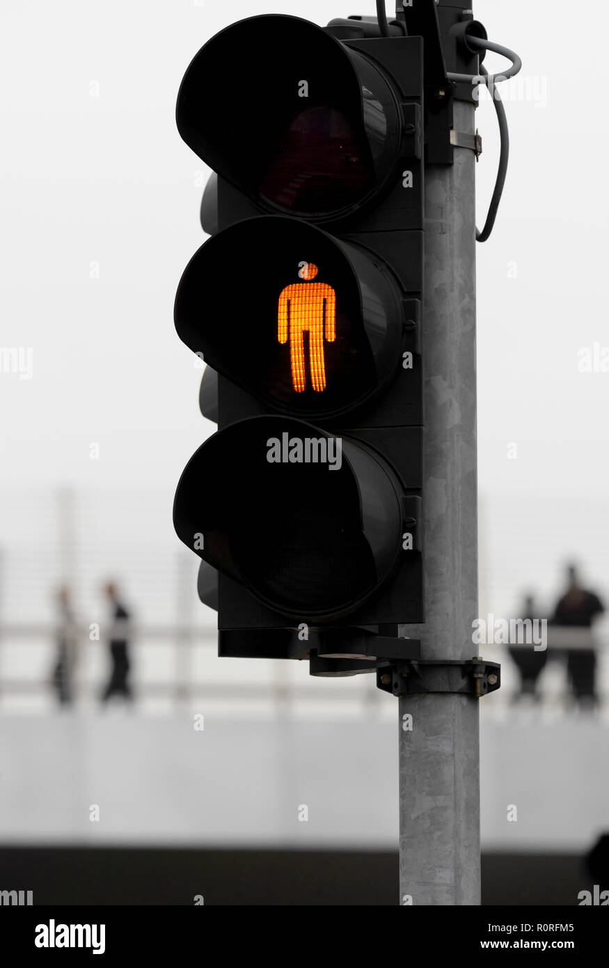 Orange semaforo con persone in background Foto Stock