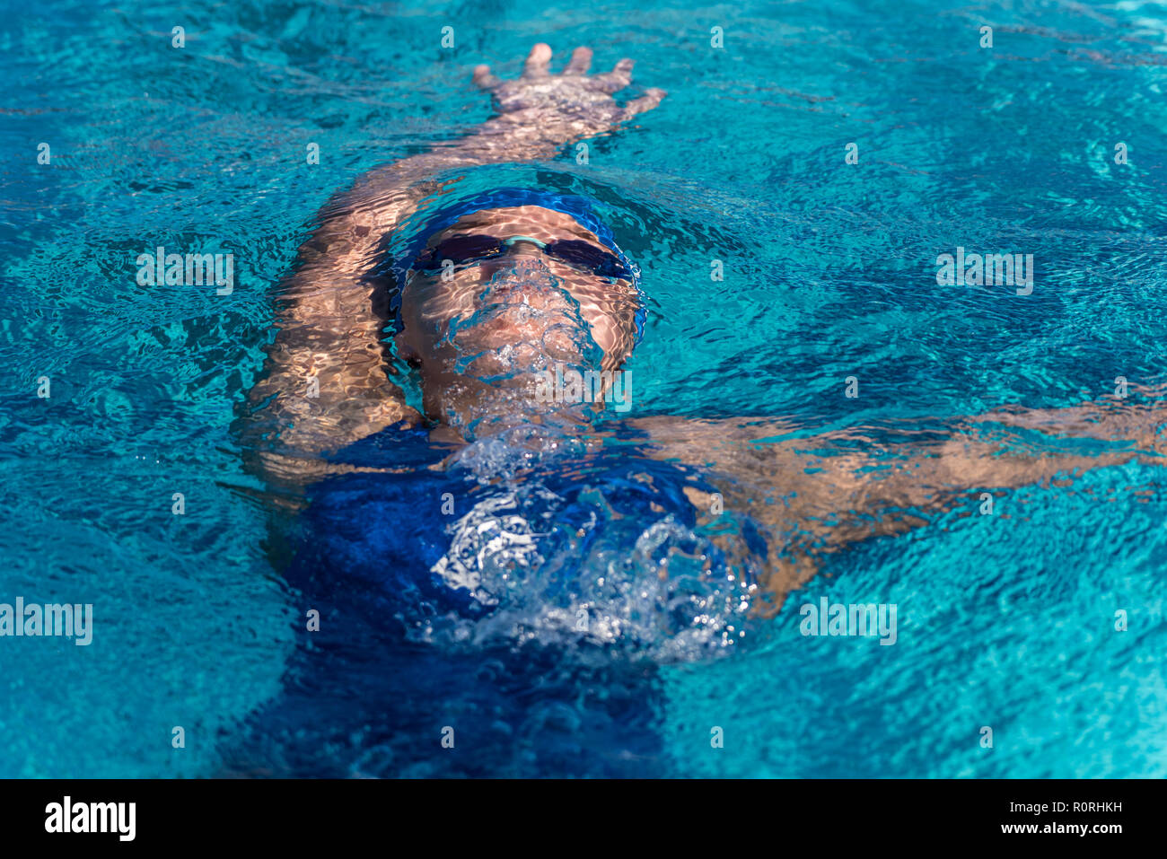 Nuotatore femmina ancora sommersa mentre ascende alla superficie della piscina dopo flip girare durante la nuotata soddisfare gara. Foto Stock