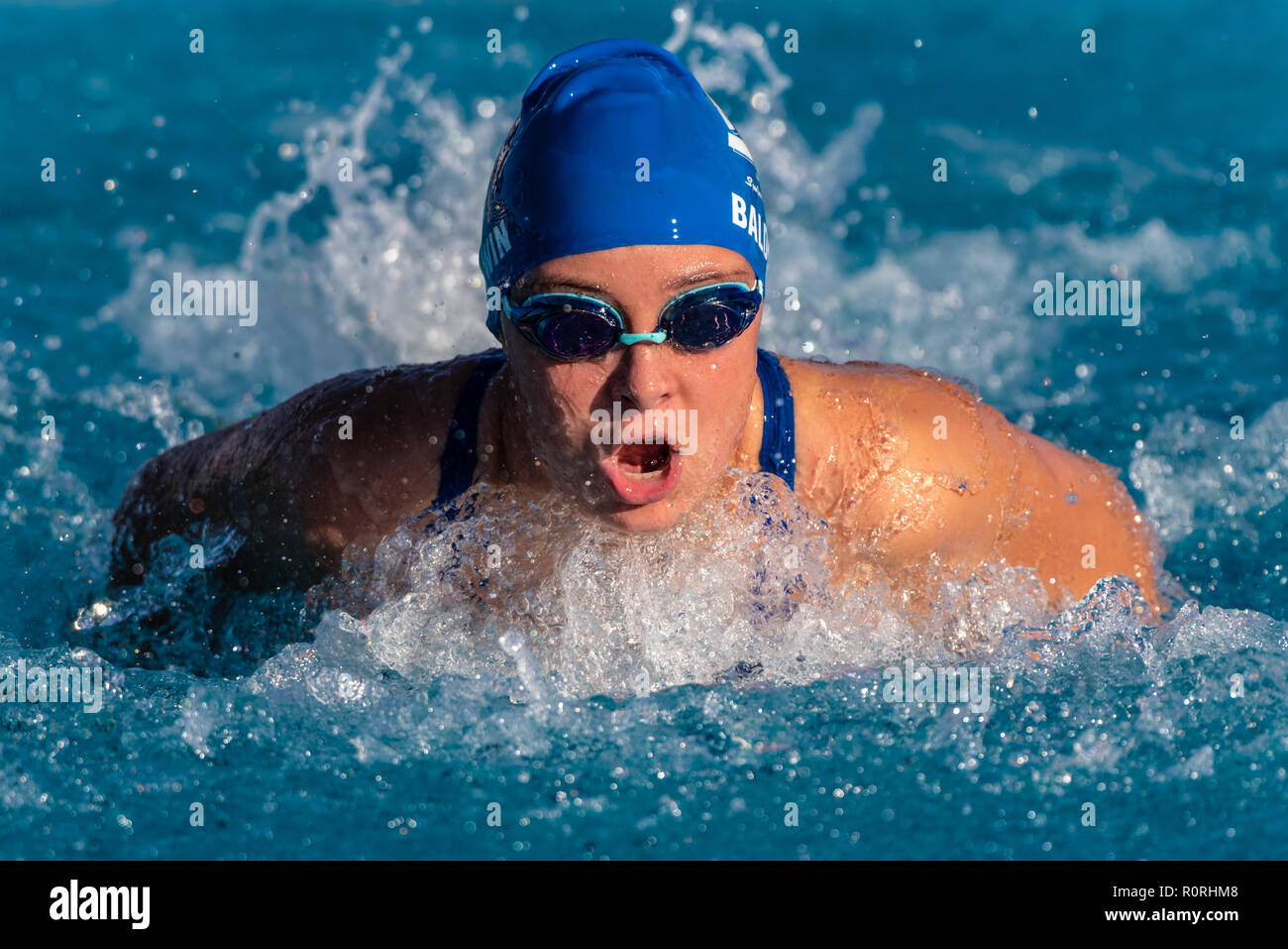 Femmina competitivo nuotatore arrivando fino a respirare durante la potente corsa farfalla durante la gara. Foto Stock