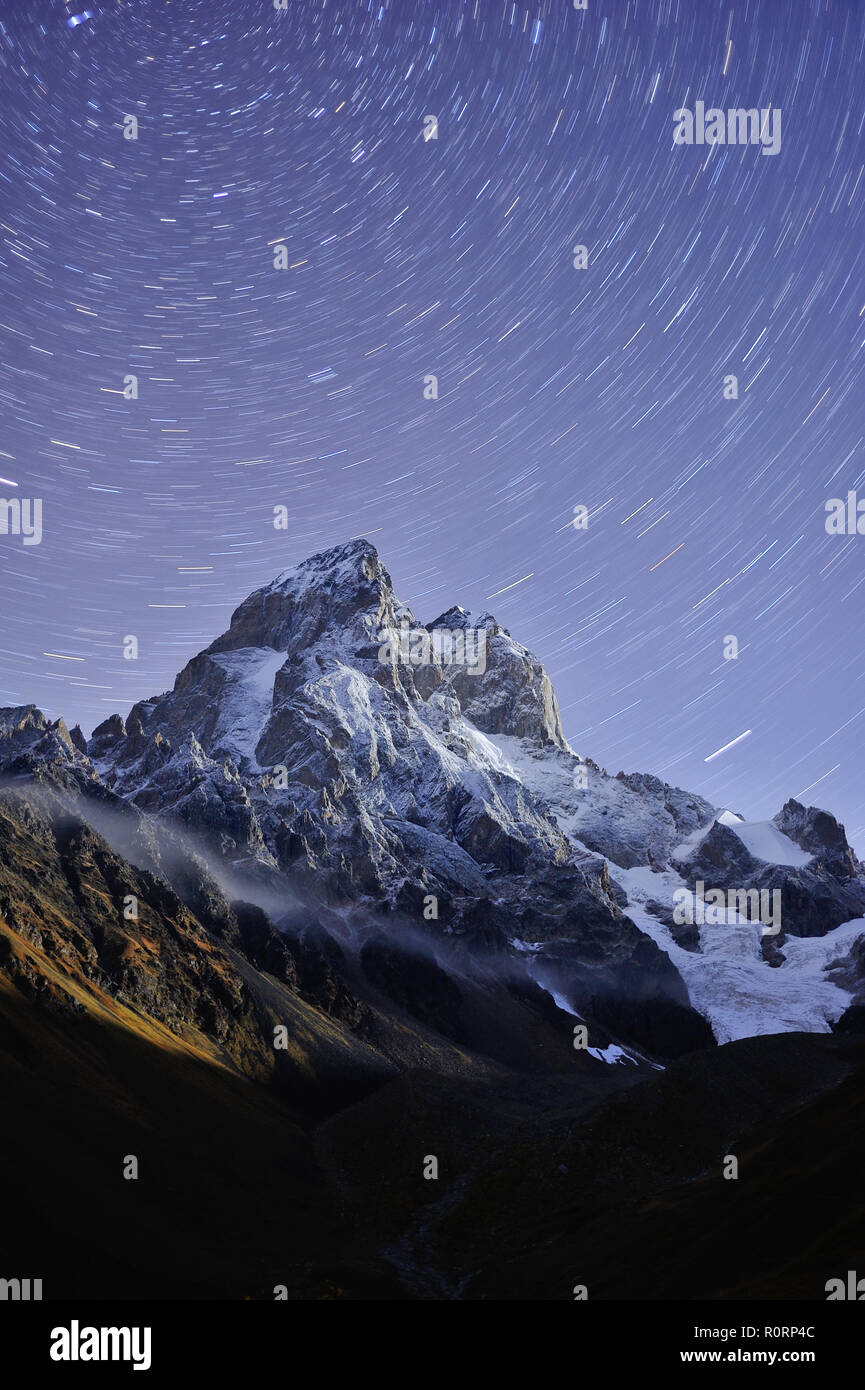 Tracce stellari oltre la montagna Ushba in Georgia, Zemo Svaneti. Notte paesaggio di montagna. Foto Stock