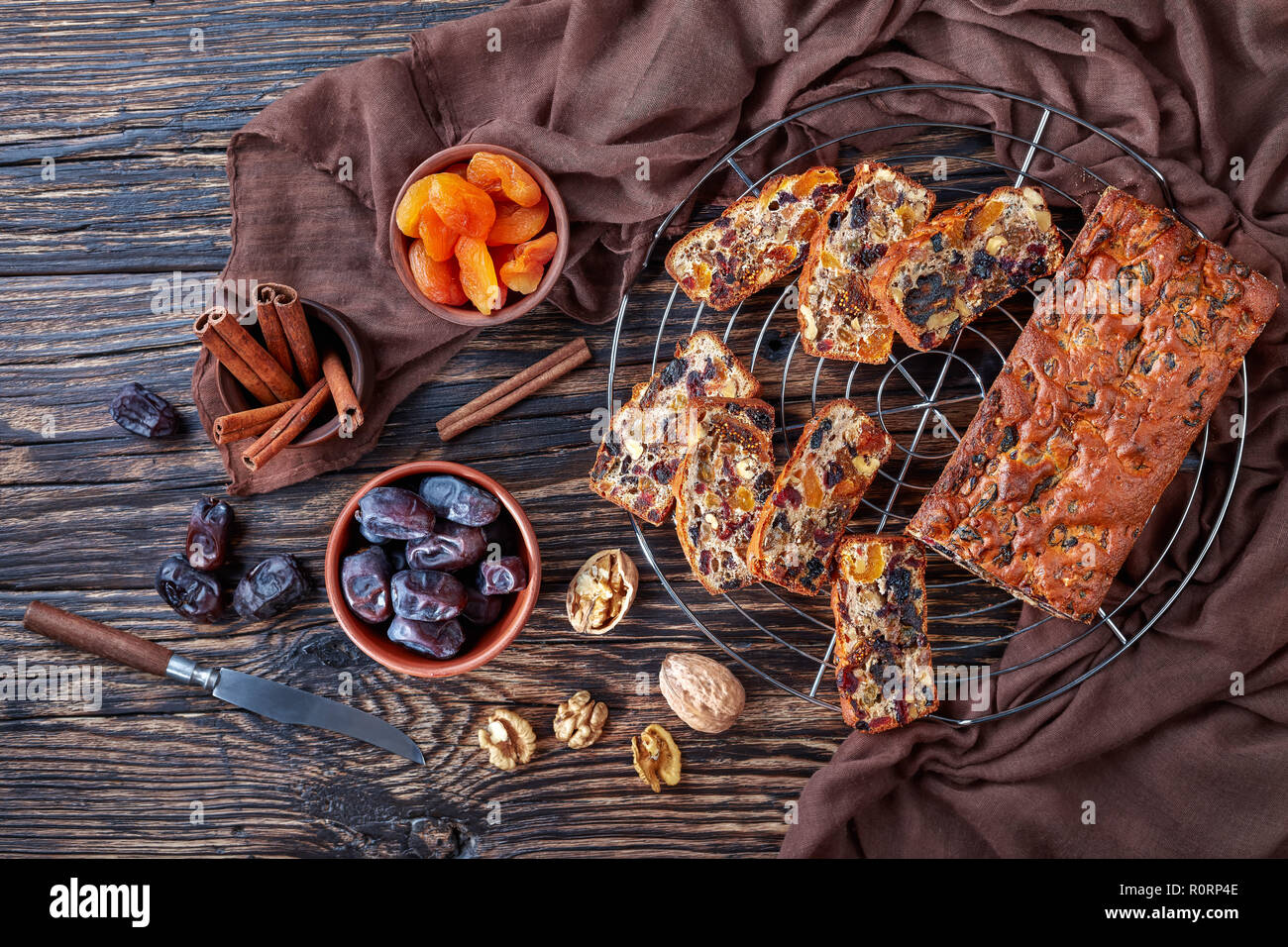 Deliziosa frutta secca la torta su un filo cake stand con panno marrone e gli ingredienti su un tavolo rustico, vista da sopra, flatlay, spazio di copia Foto Stock