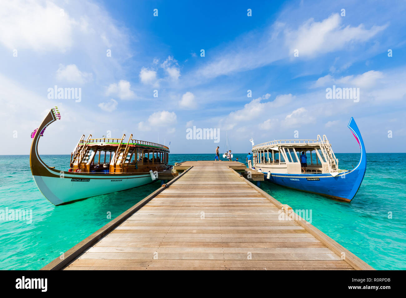 Meravigliose barche maldiviano Dhoni sulla tropicale mare blu al molo in legno dock, tenendo turista per lo snorkeling e le immersioni per vedere la fauna subacquea Foto Stock