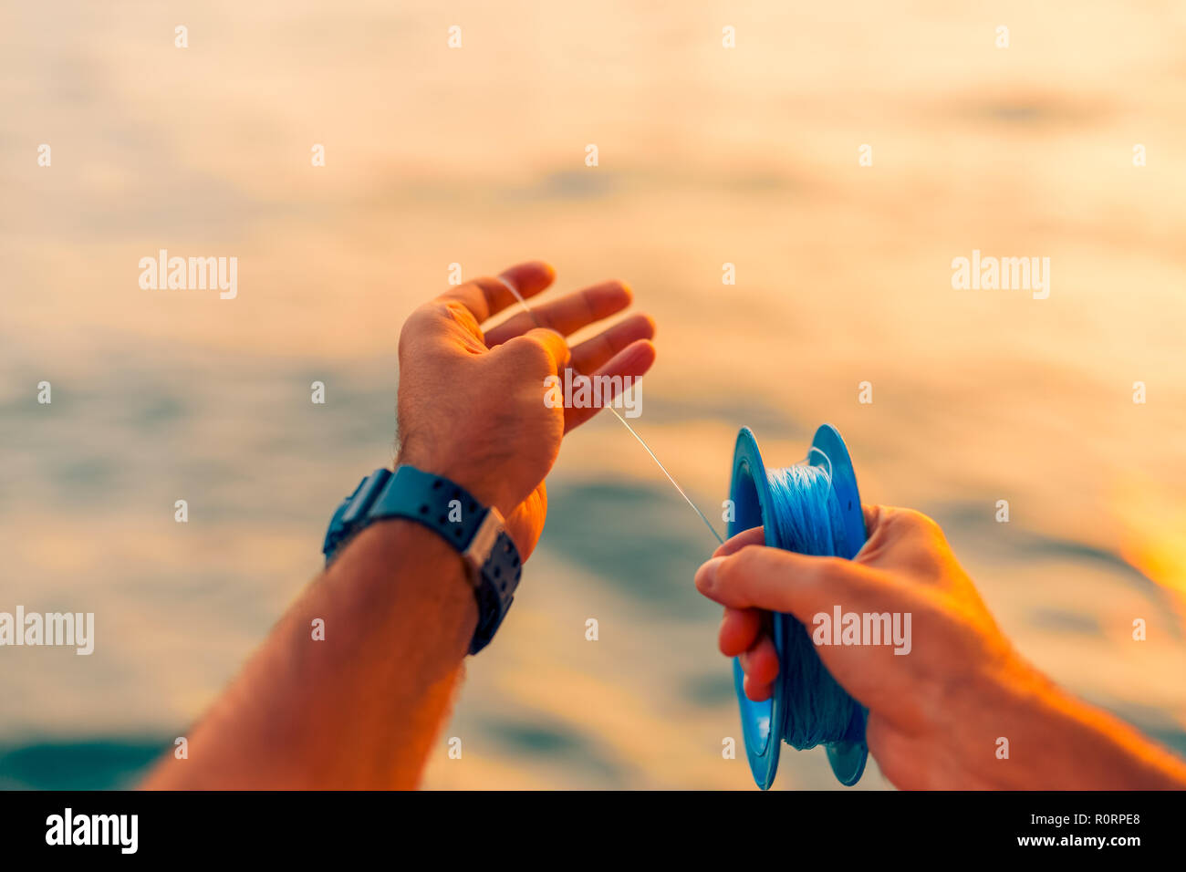Ben utilizzato linea di mano e il mulinello da pesca in mare tropicale. Sfocata sullo sfondo del mare. Acqua relativa allo sport e al tempo libero lo sfondo Foto Stock