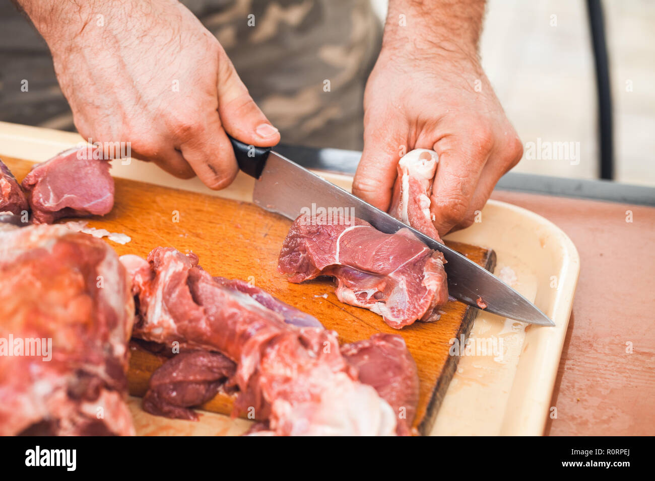 Carne di agnello, di taglio forte cuocere le mani con il coltello. Close-up foto, messa a fuoco selettiva Foto Stock