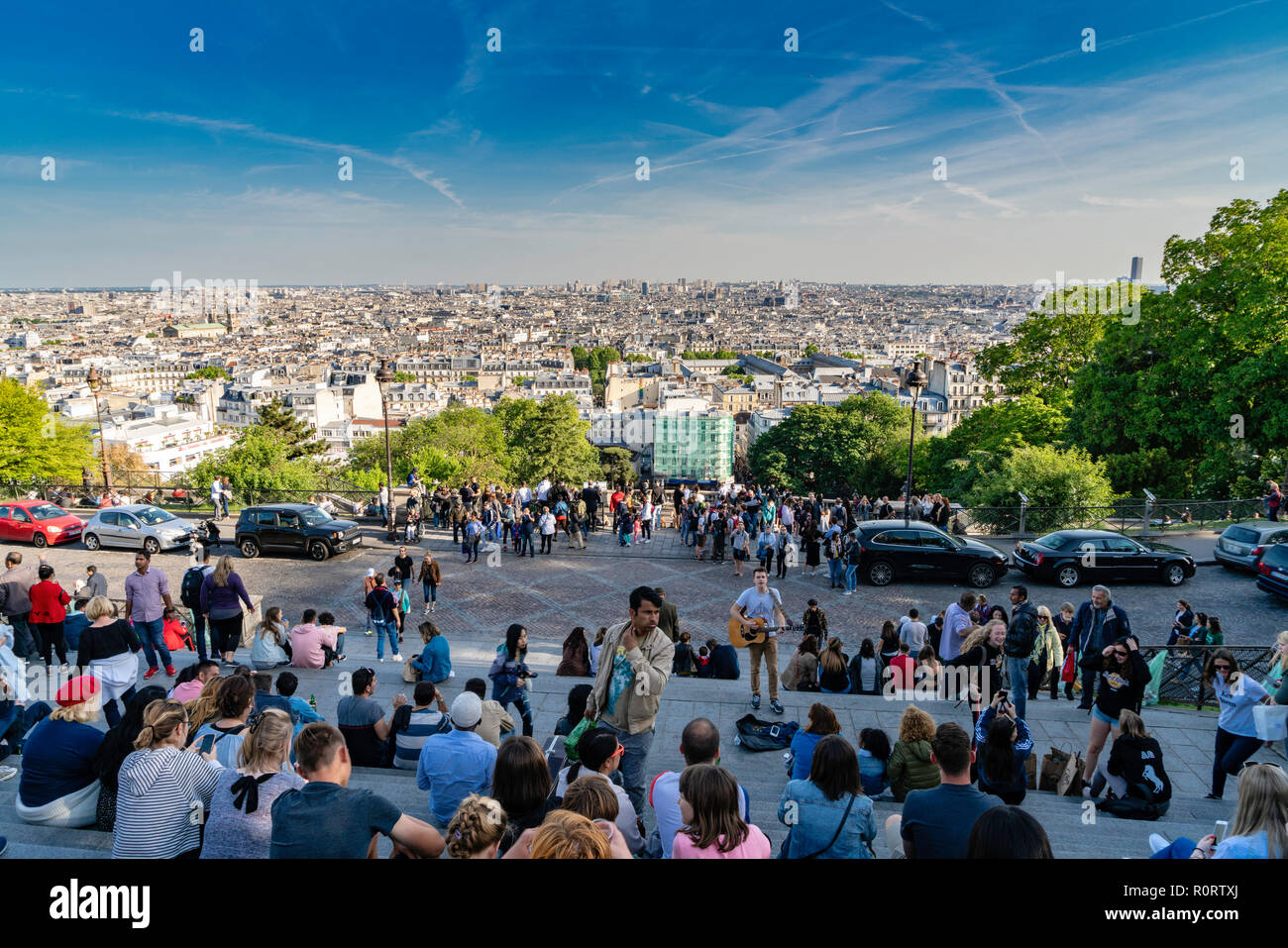 Turisti che si siedono sui passi di te della Basilica del Sacre Coeur di Montmartre, a guardare la città di Parigi, Francia Foto Stock