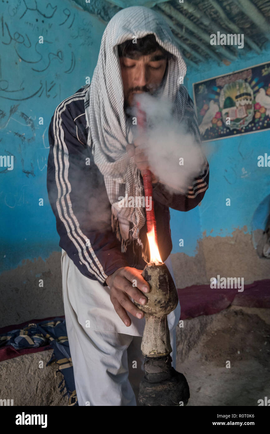 Uomo di fumare hashish con un bong vicino alla tomba di un santo Sufi, antica Balkh, Nord Afghanistan Foto Stock