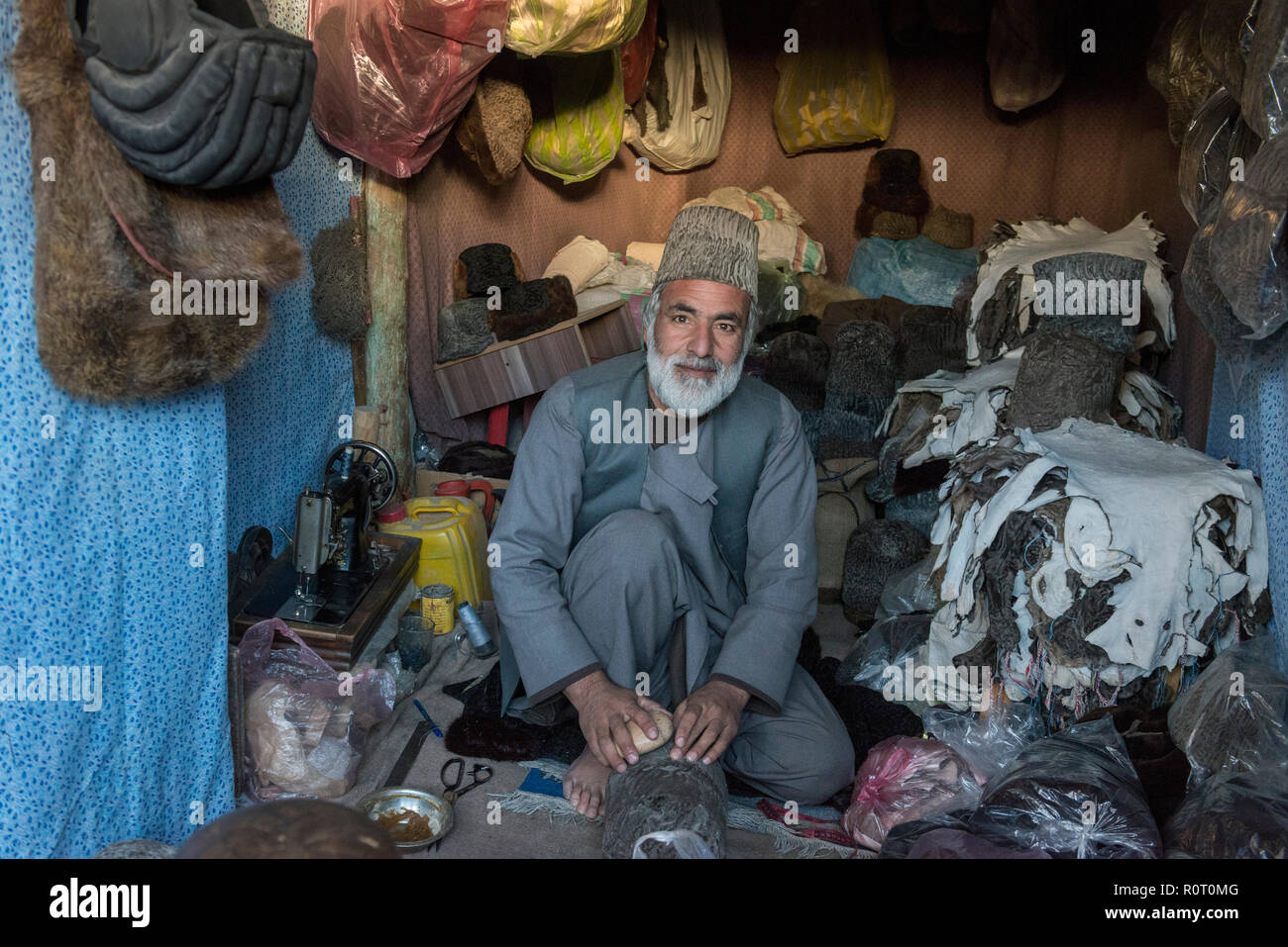 Uomo di fabbricazione di cappelli di pelliccia in stallo colorato a Mazar-e Sharif Central Bazaar, Maraz-e Sharif, Balkh Provincia, Afghanistan Foto Stock