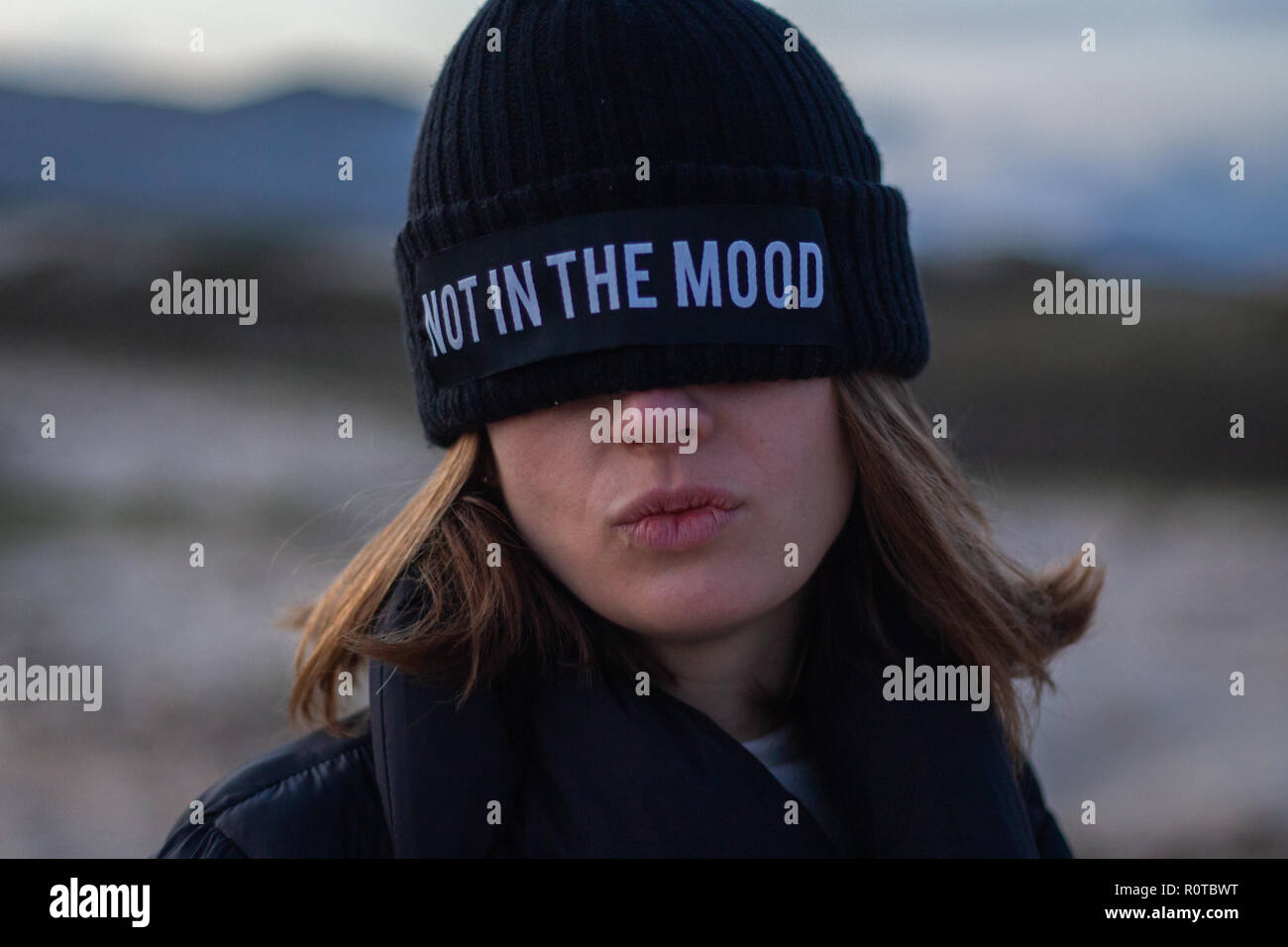 Ragazza che indossa un cappello nero che copre la sua gli occhi con la dicendo che non è dell'umore Foto Stock