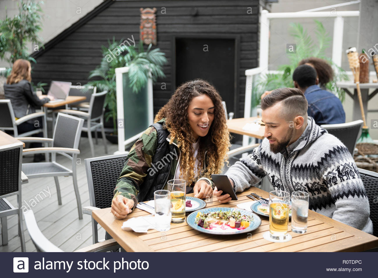 Coppia con smart phone godendo il pranzo sul patio cafe Foto Stock