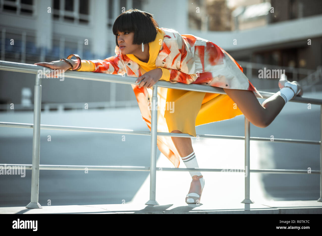 Dai capelli scuri con lady orecchini bianchi nel lanciare una gamba sopra la tromba Foto Stock