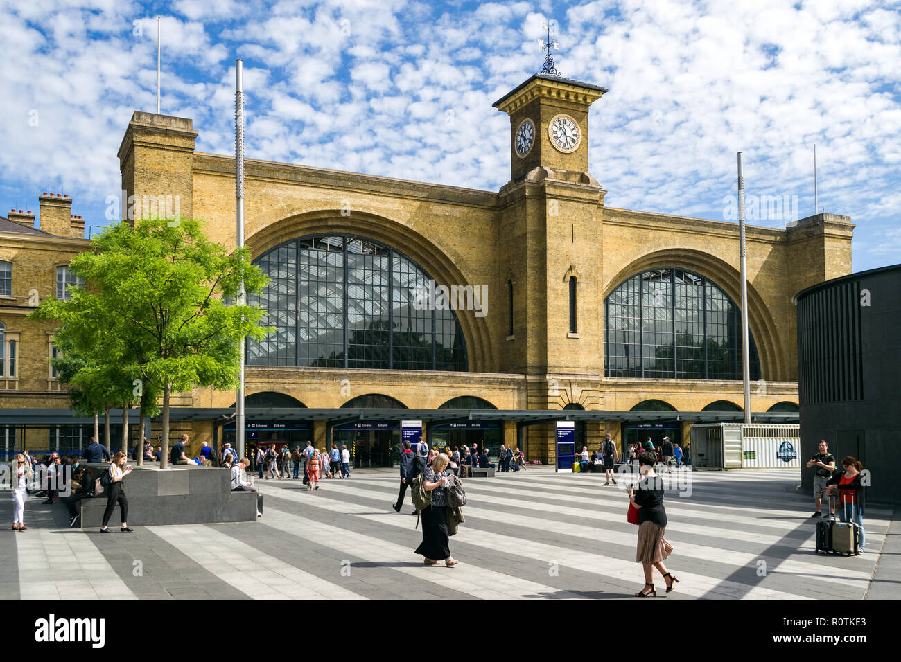 Esterno plaza di Kings Cross stazione ferroviaria su una soleggiata mattina d'Estate con la gente camminare al di fuori di Londra, Regno Unito Foto Stock