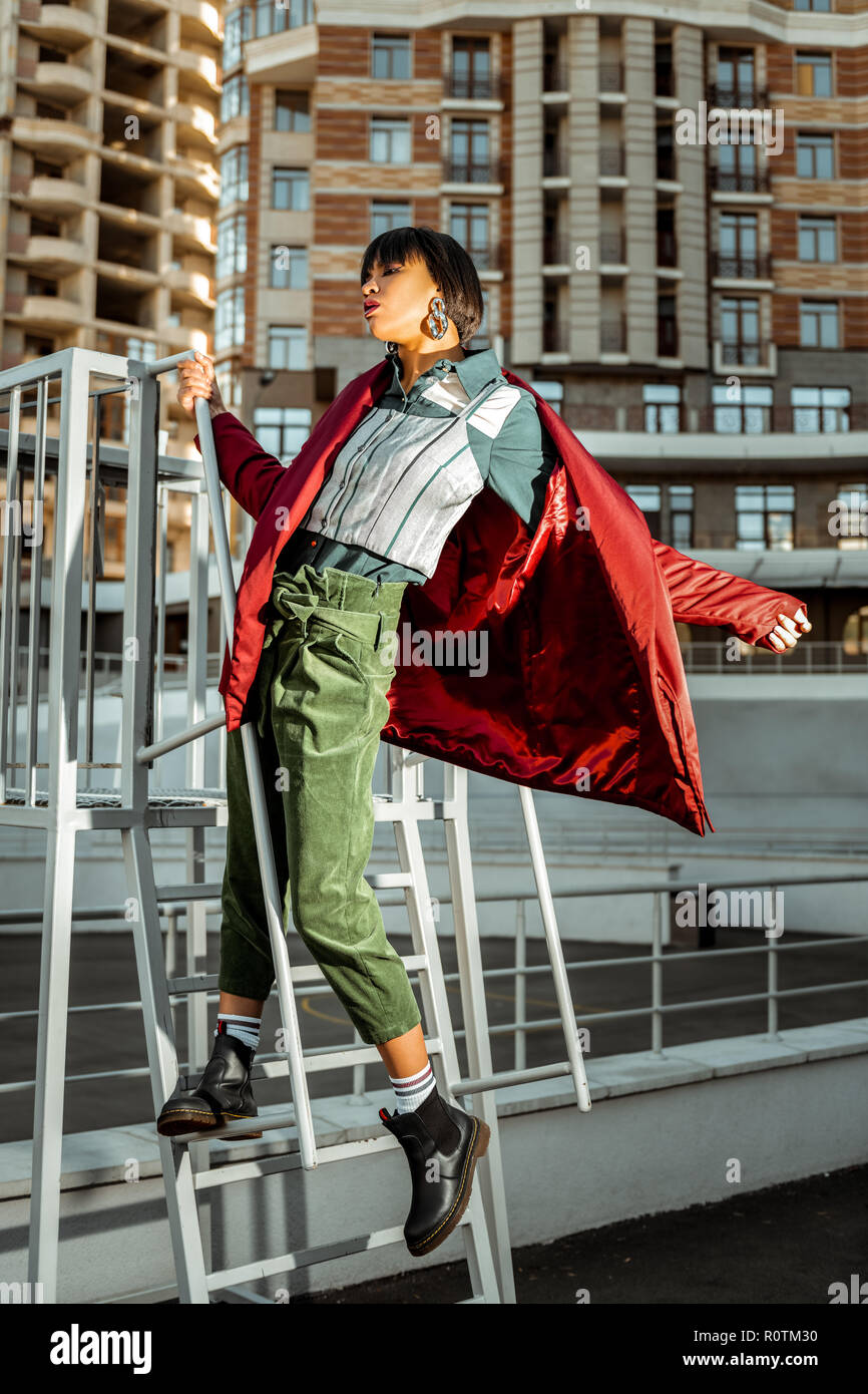 Singolare gara di misto ragazza tenendo disattivato il suo rosso mantello lucido Foto Stock
