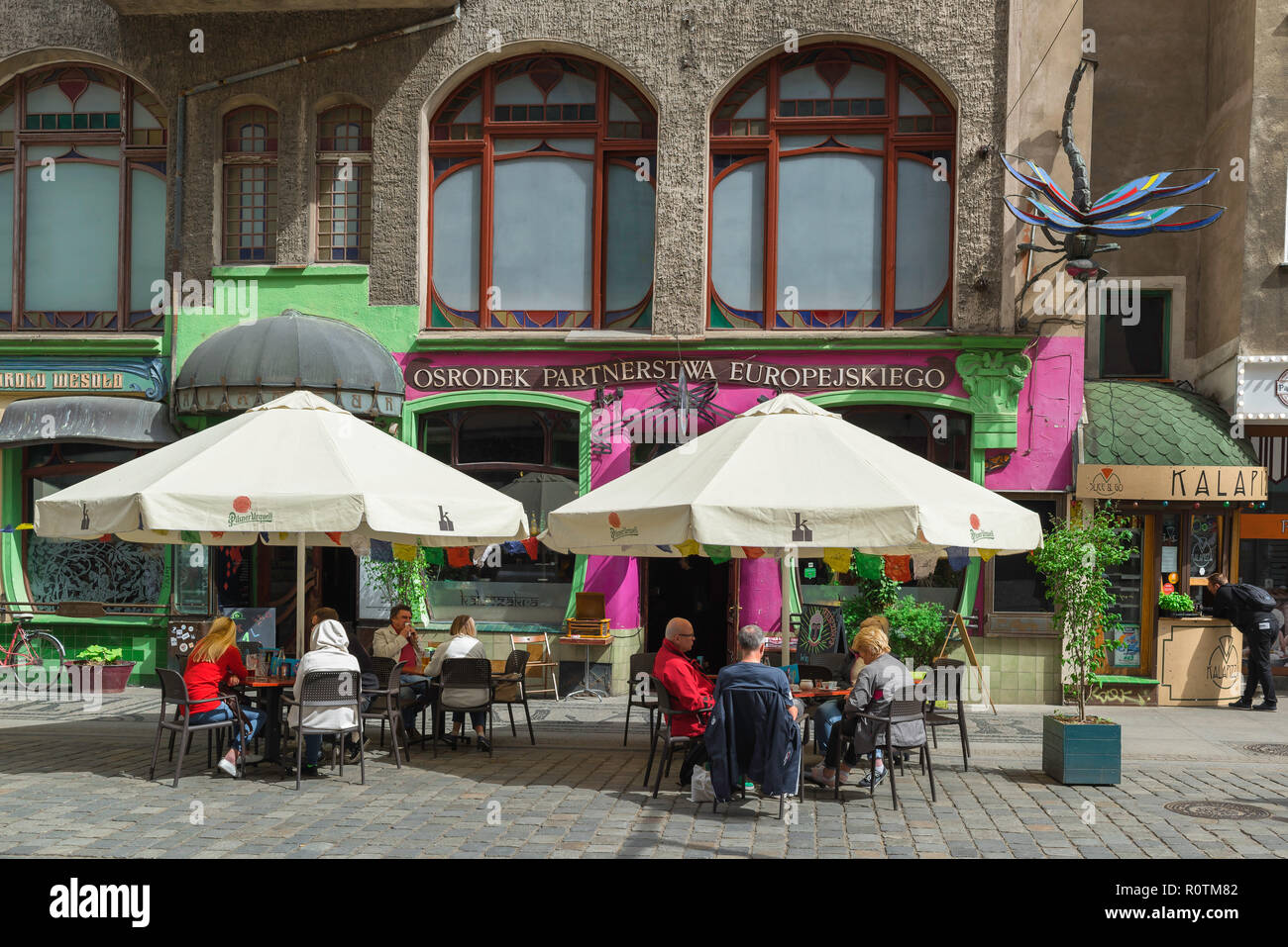 Wroclaw cafe, vista di persone in un momento di relax a tavoli fuori il coloratissimo e bizzarro Art Cafe e Bar Kalambur nel quartiere universitario di Wroclaw, Polonia Foto Stock