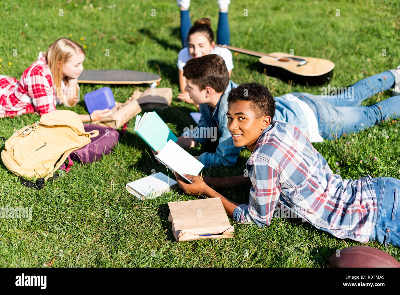 Gruppo di felice teen studiosi giacente su erba e studiare insieme Foto Stock