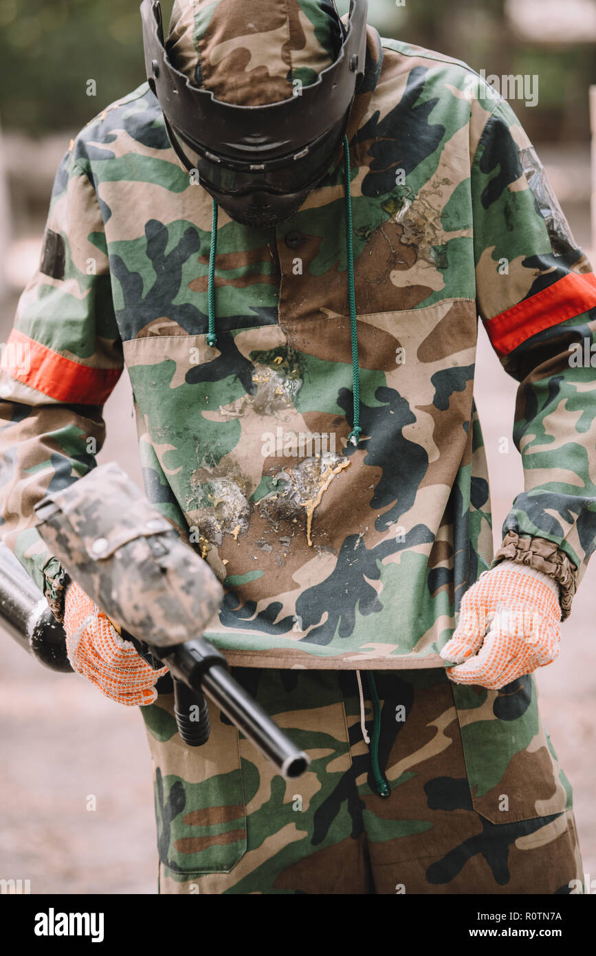 Lettore di paintball con marcatore Gun guardando il camuffamento coperti da paintball splash all'aperto Foto Stock