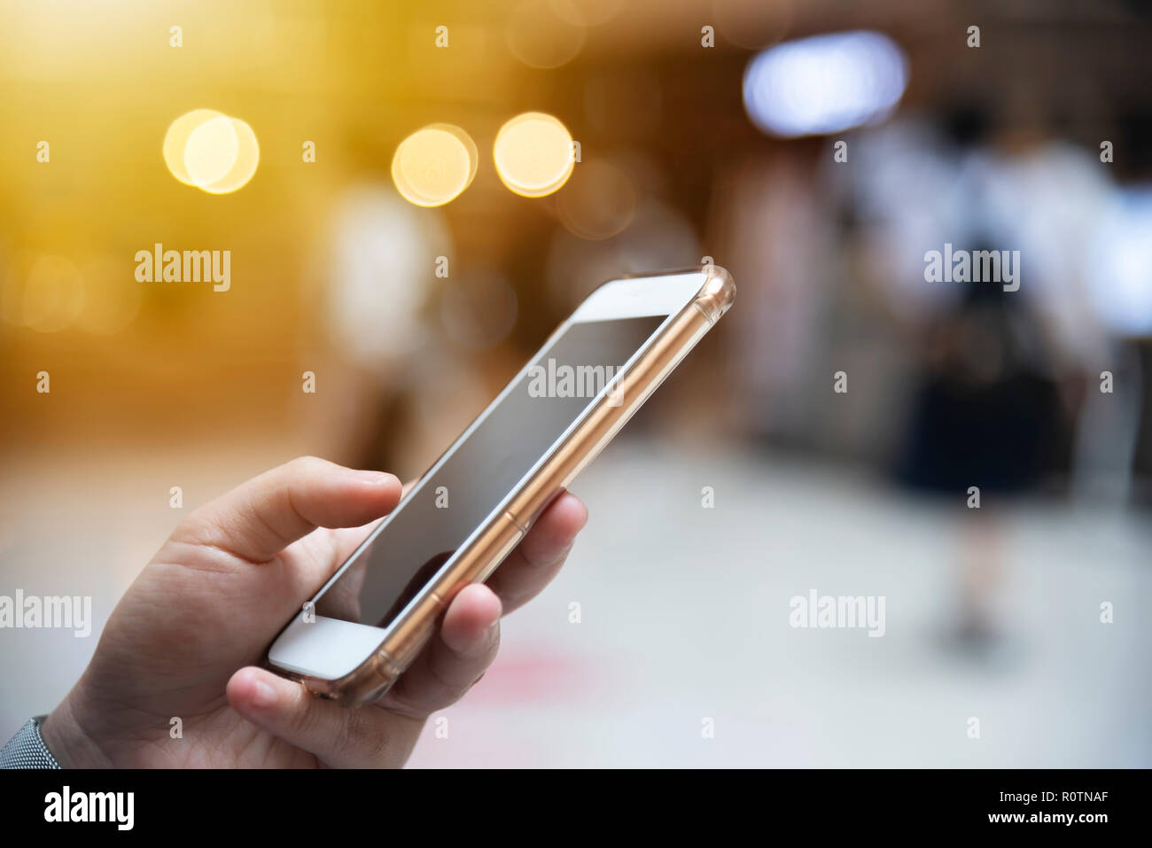 Primo piano della mano di persone che lavorano online nel mobile con città sfocata luce sulla strada dello sfondo. Moderna connessione wireless tecnologia per lo stile di vita Foto Stock