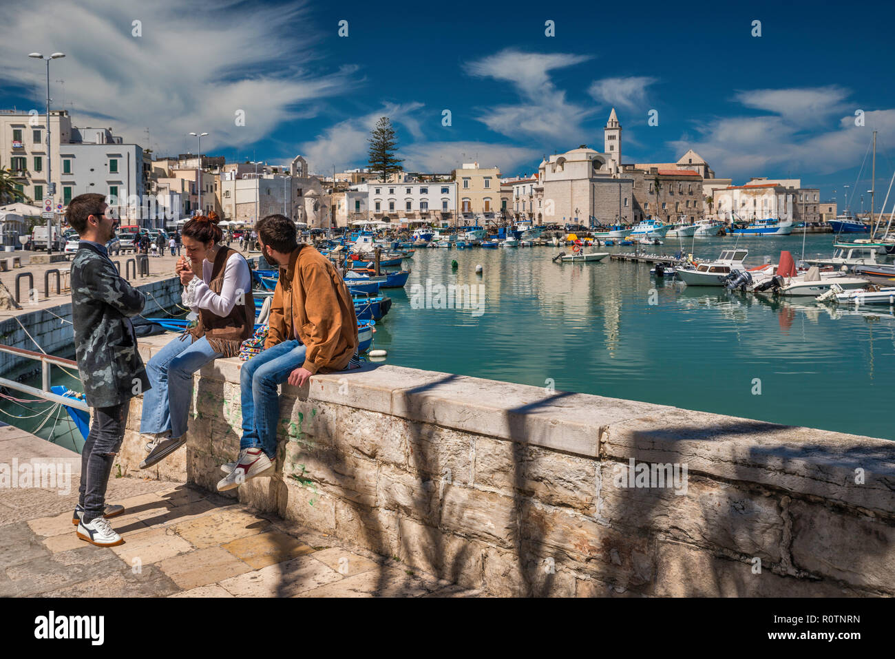 Il gruppo di amici a waterfront, centro storico in distanza, Trani, Puglia, Italia Foto Stock